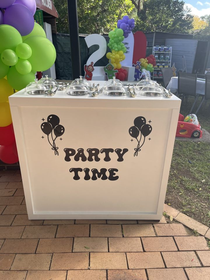 White party trolley with Party Time text and balloon decals, topped with four glass serving domes.