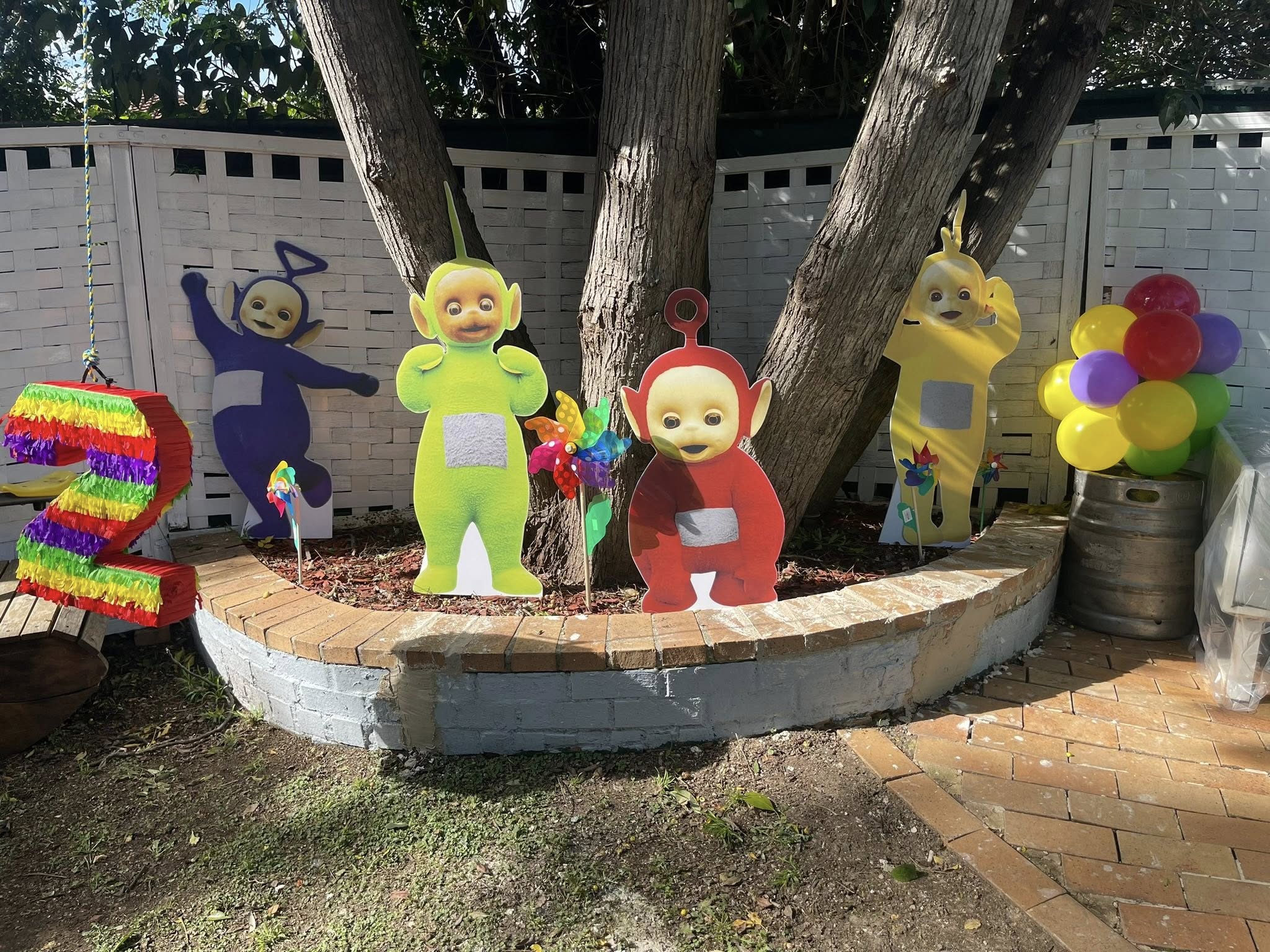Teletubbies yard decorations with a number 2 pinata and colorful balloons for a child's birthday.