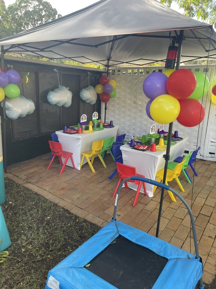 Colorful children's party tables with balloons and chairs set up under a marquee
