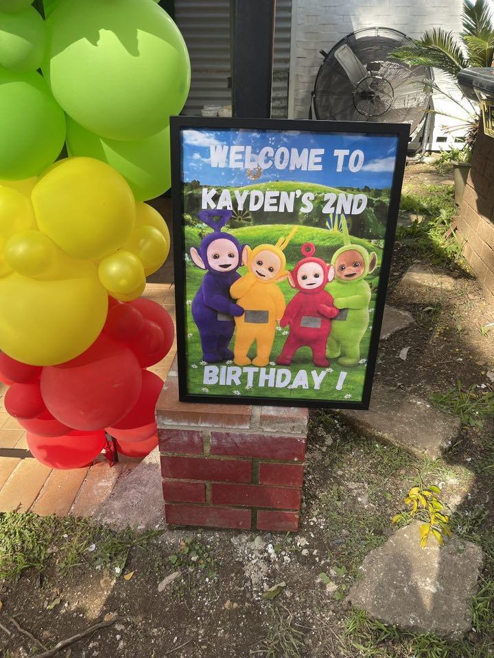 Welcome to Kayden's 2nd Birthday sign featuring Teletubbies characters with a balloon arch decoration.