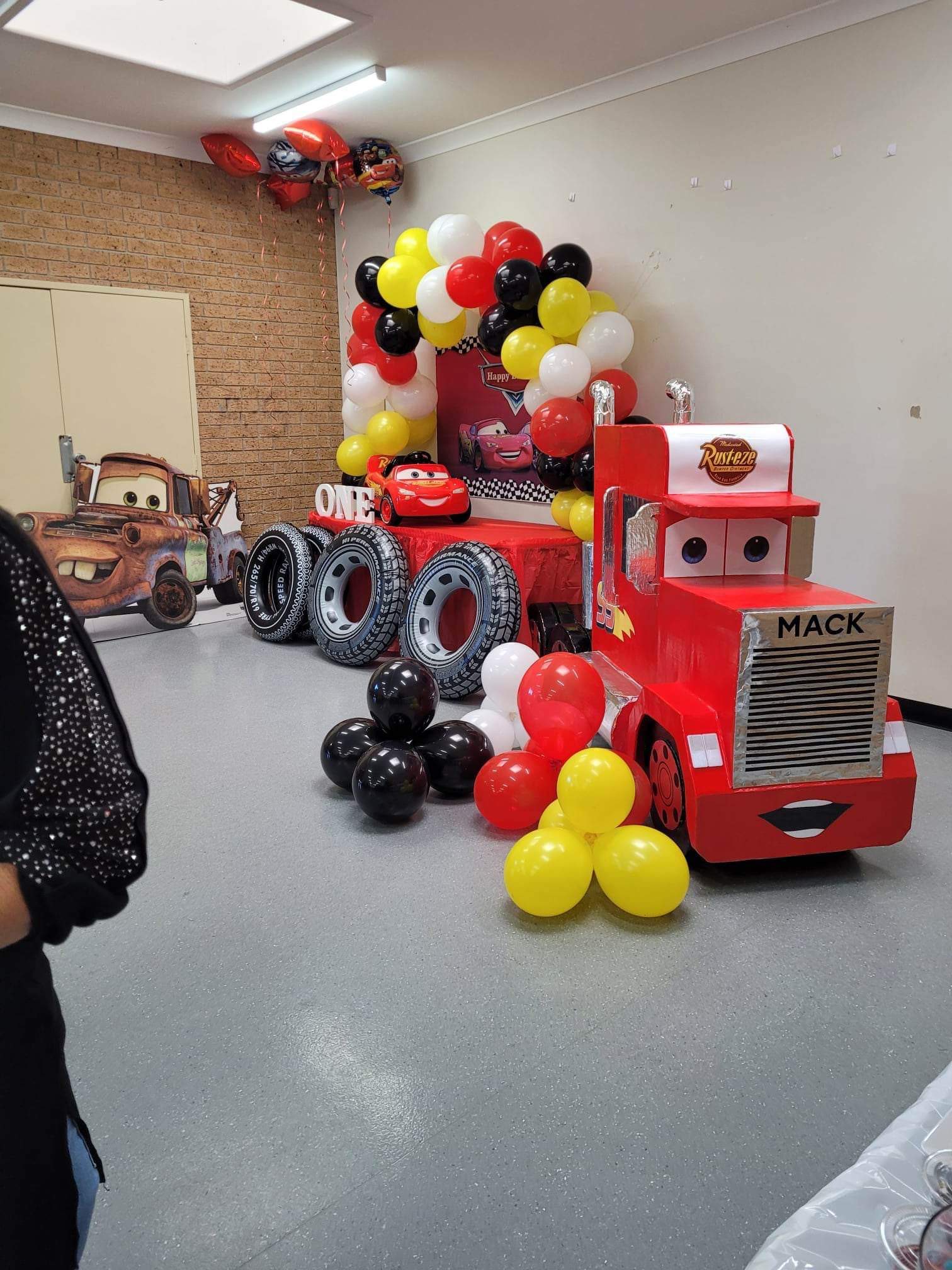 Cars themed party display with red truck, balloon arch, and Mater cutout.