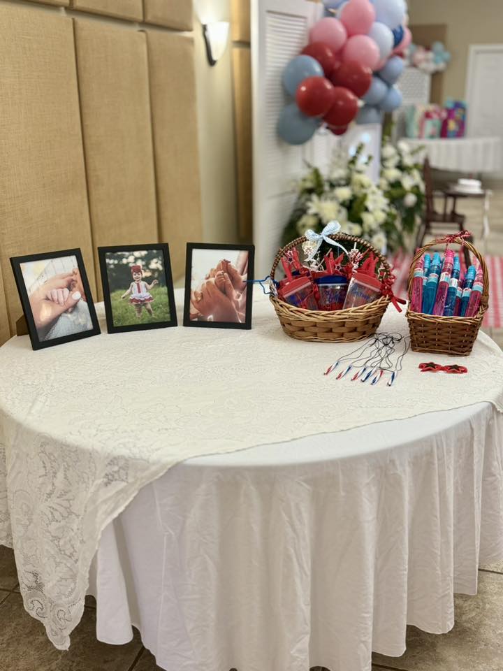 Table decorated with framed photos of a child and baskets of party favors.