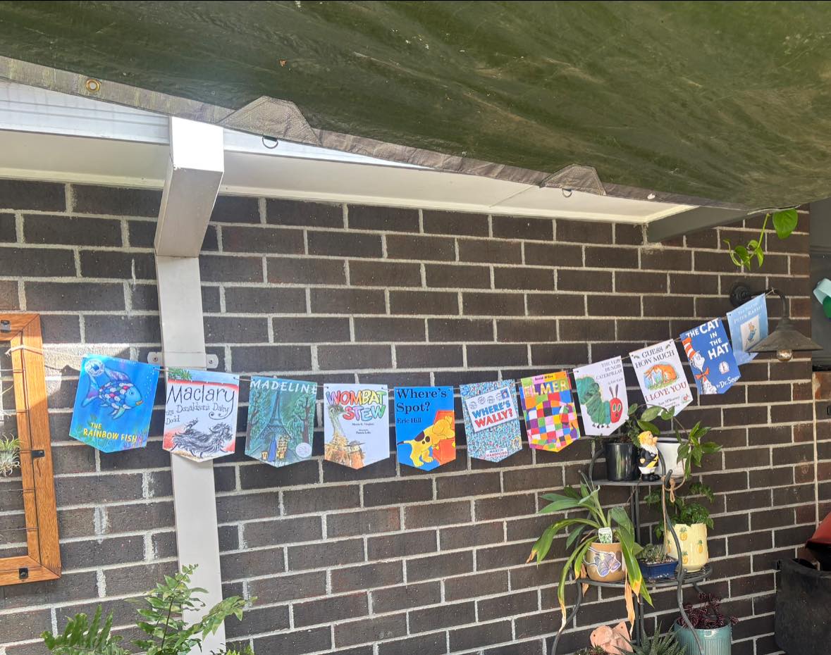 Bunting featuring covers of popular children's books hung against a brick outdoor wall.