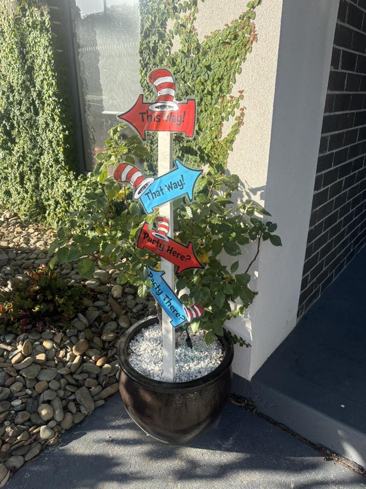 Dr. Seuss themed party directional sign with red, blue, and striped Cat in the Hat style markers.