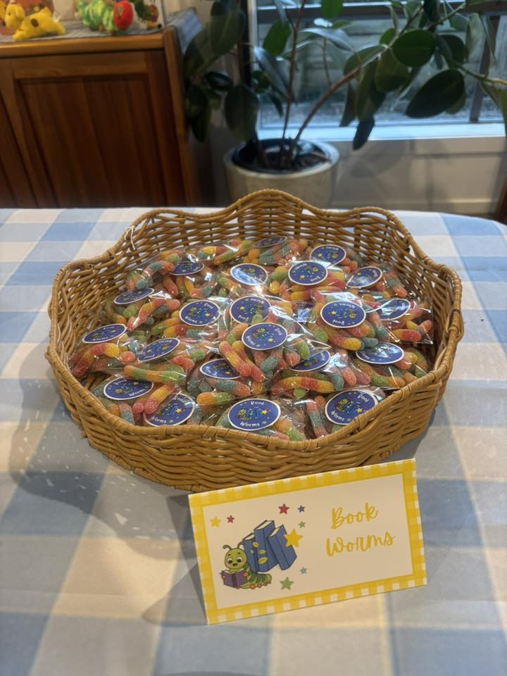 Basket filled with individually wrapped gummy worms labeled Book Worms, with a matching sign on the table.