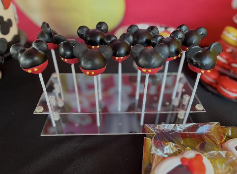 Mickey Mouse shaped cake pops on a clear acrylic display stand