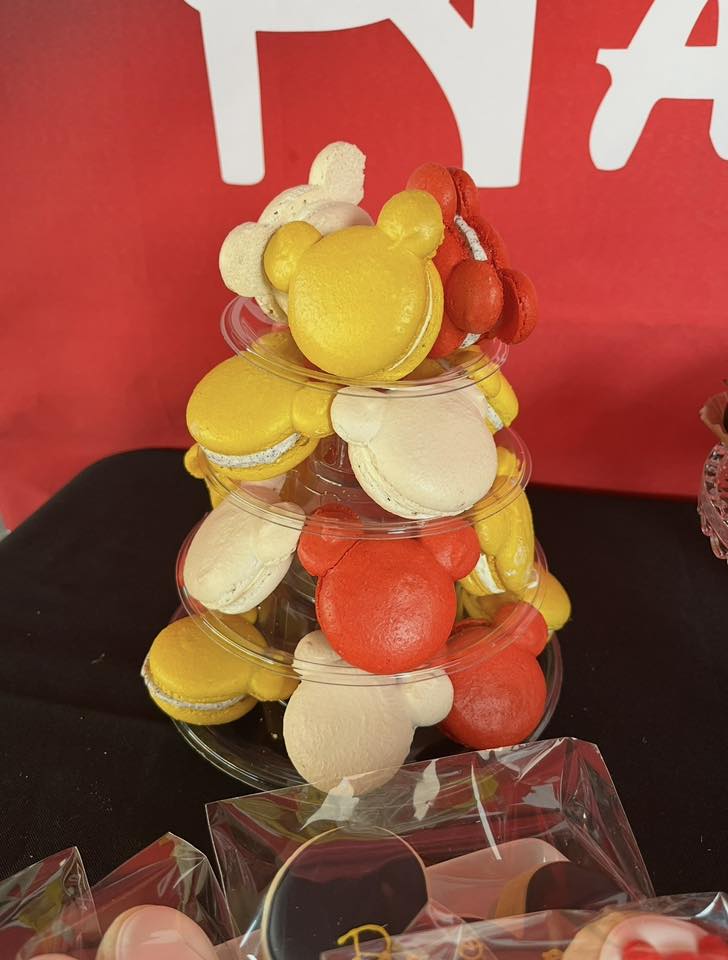 Tiered display of assorted red, yellow, and cream colored Mickey Mouse-shaped macarons
