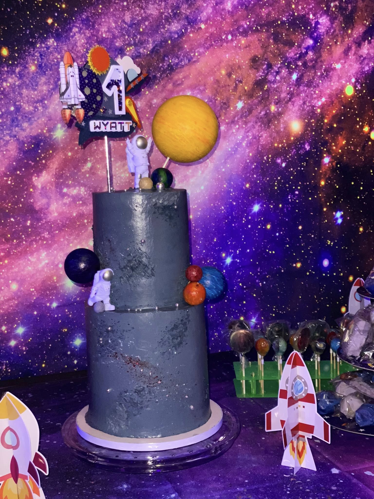Two-tier space-themed birthday cake with astronaut and planet decorations for Wyatt's 4th birthday.