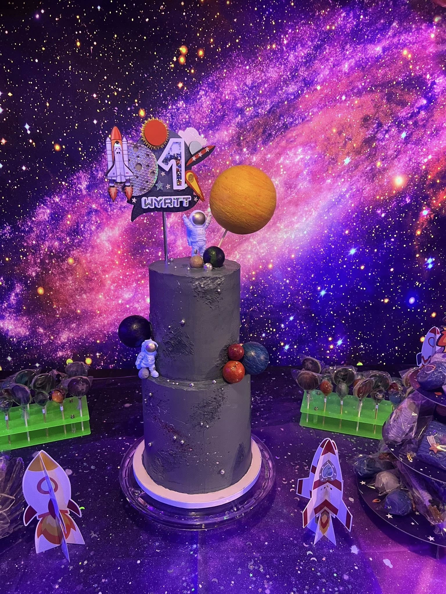 Two-tier space-themed birthday cake for Wyatt aged one, featuring astronaut and planet decorations.