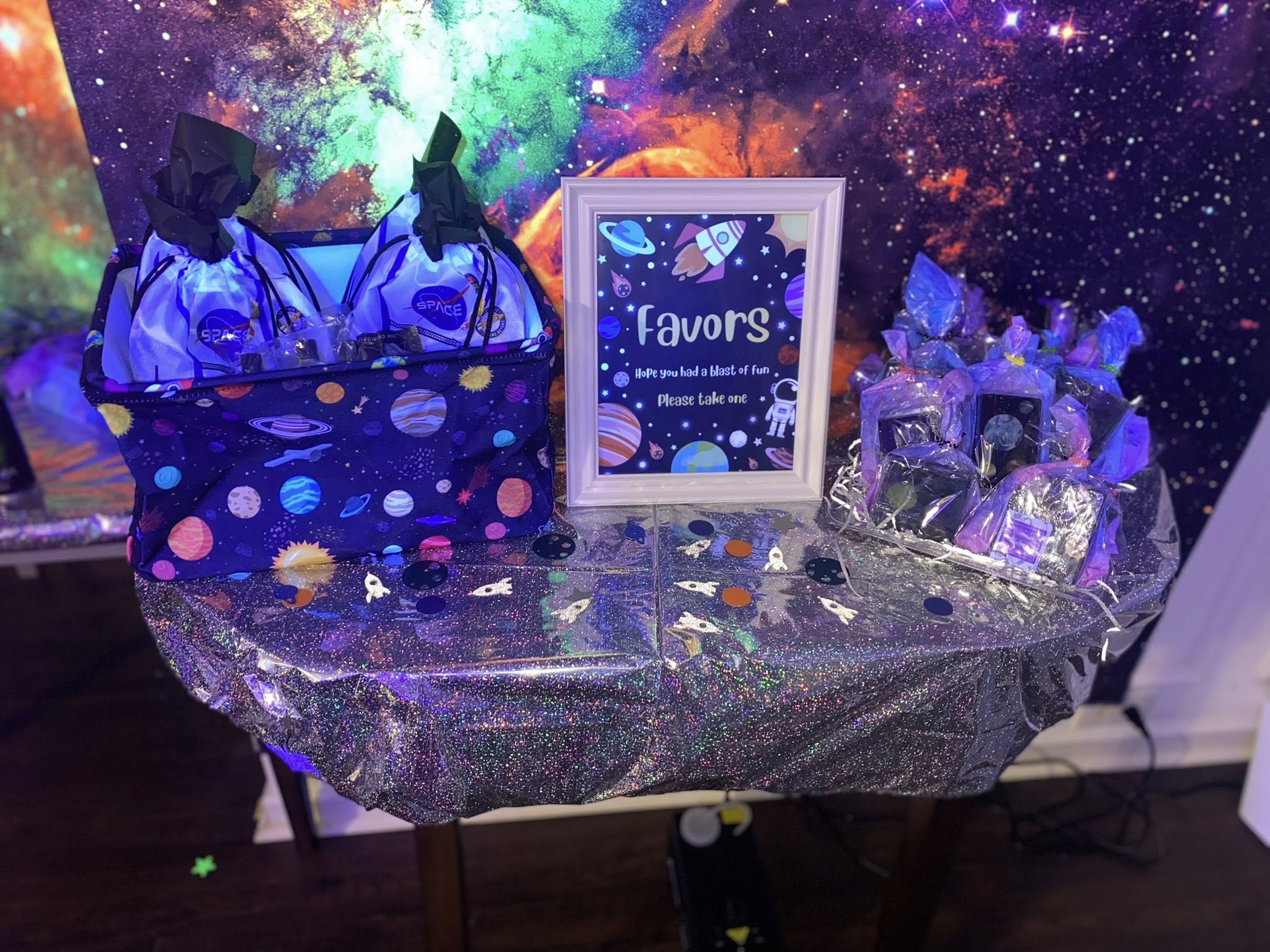 Space themed party favor table with gift bags and a sign that reads Favors, Hope you had a blast of fun, Please take one.