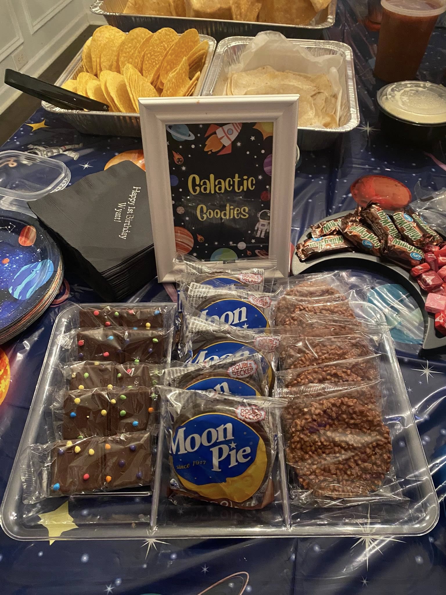 Tray of Galactic Goodies featuring Moon Pies, chocolate treats, and crispy chocolate snacks at a space-themed party.