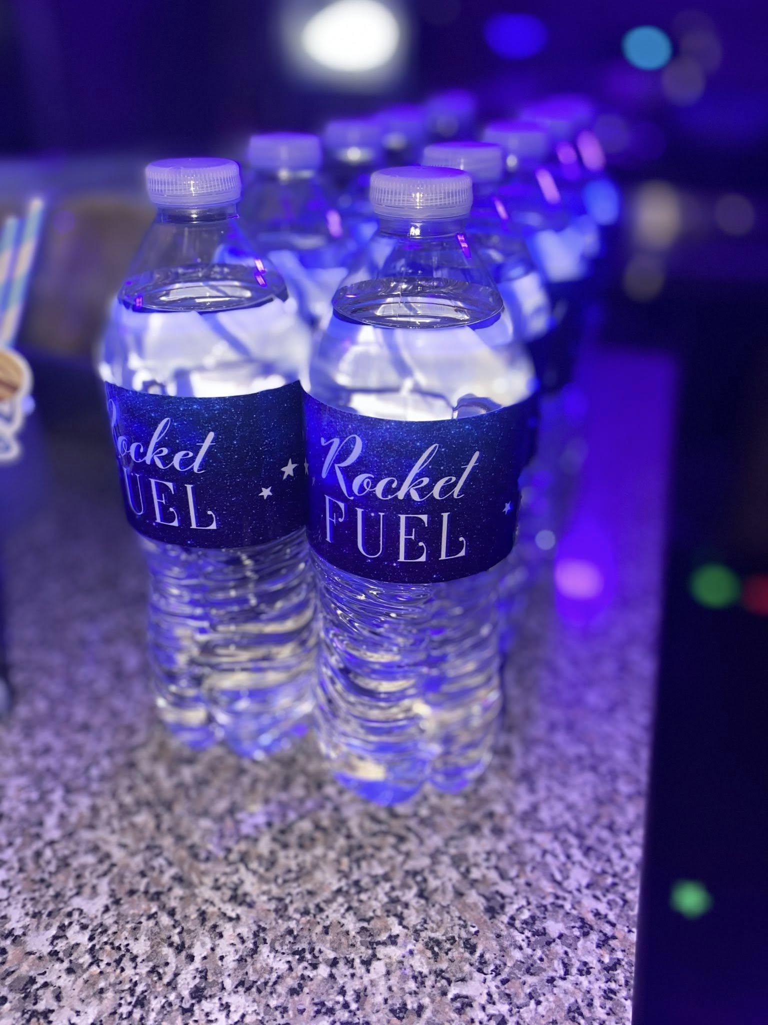 Water bottles with custom Rocket Fuel labels in a blue-lit party setting