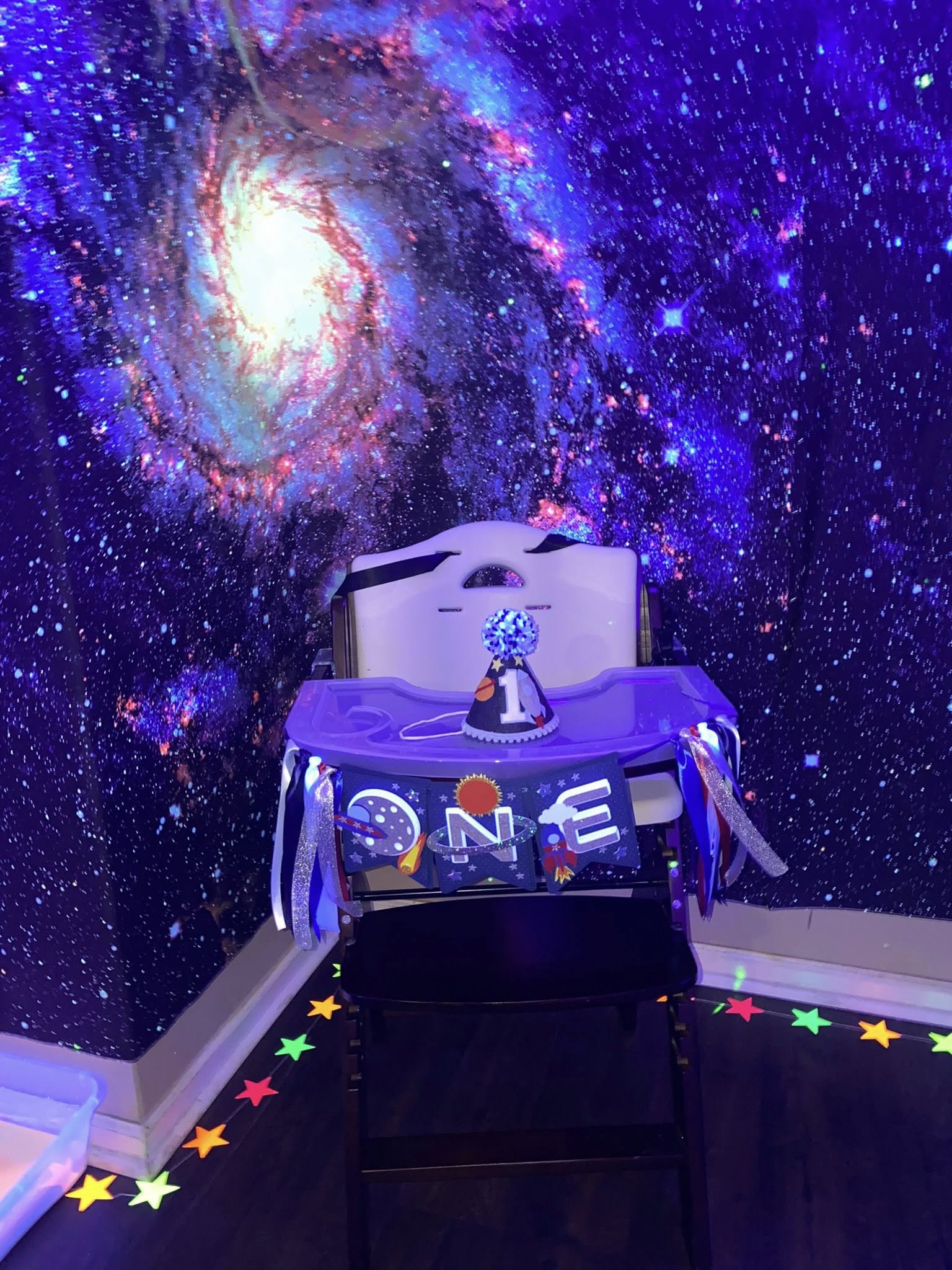 Space-themed first birthday high chair banner and matching party hat for a baby's first birthday celebration.
