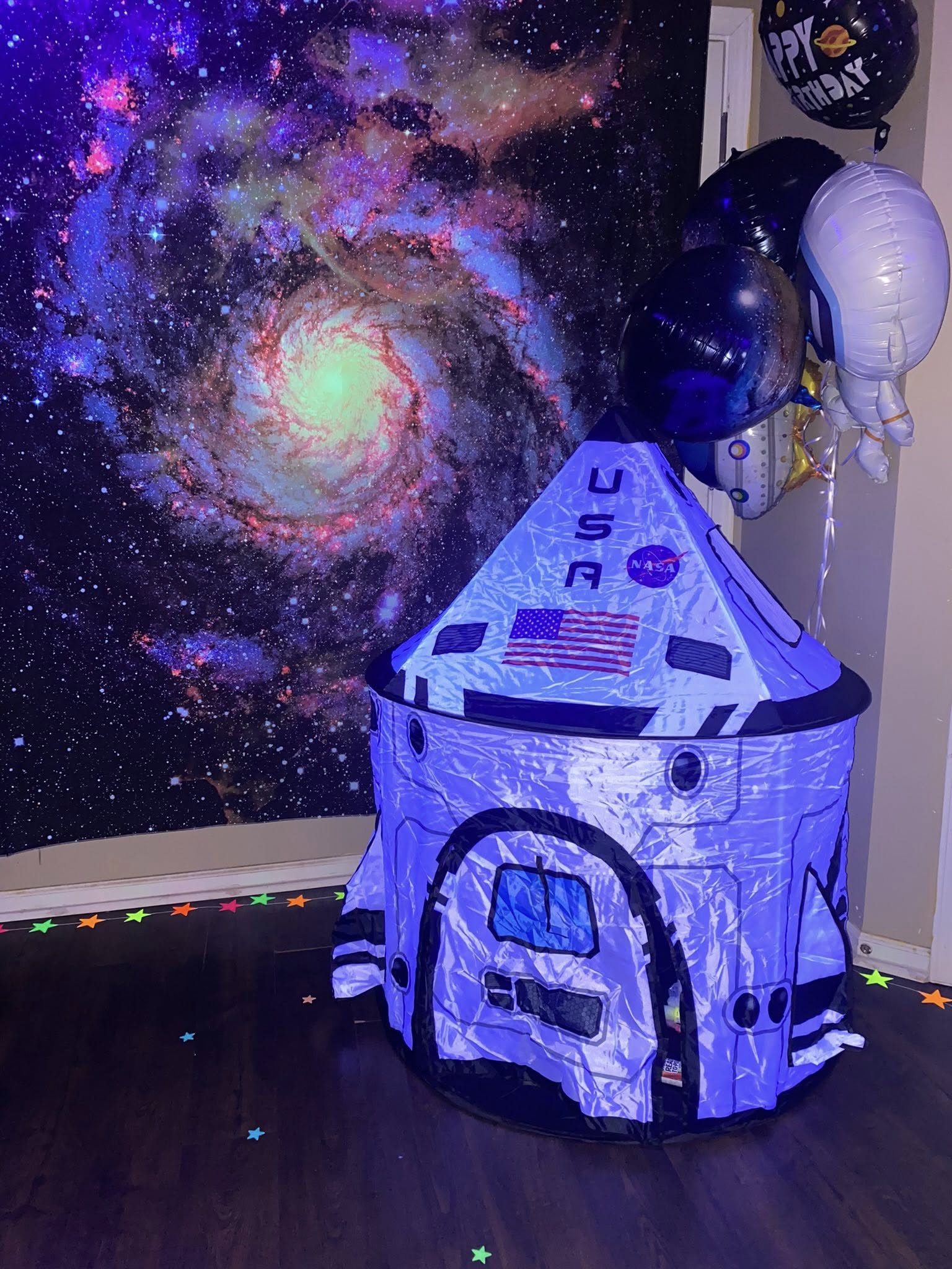 Space-themed pop-up play tent with NASA branding, displayed in front of a galaxy backdrop for a birthday setup.