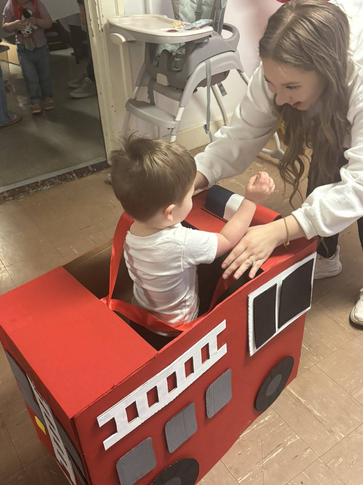 Toddler playing in a cardboard fire truck toy