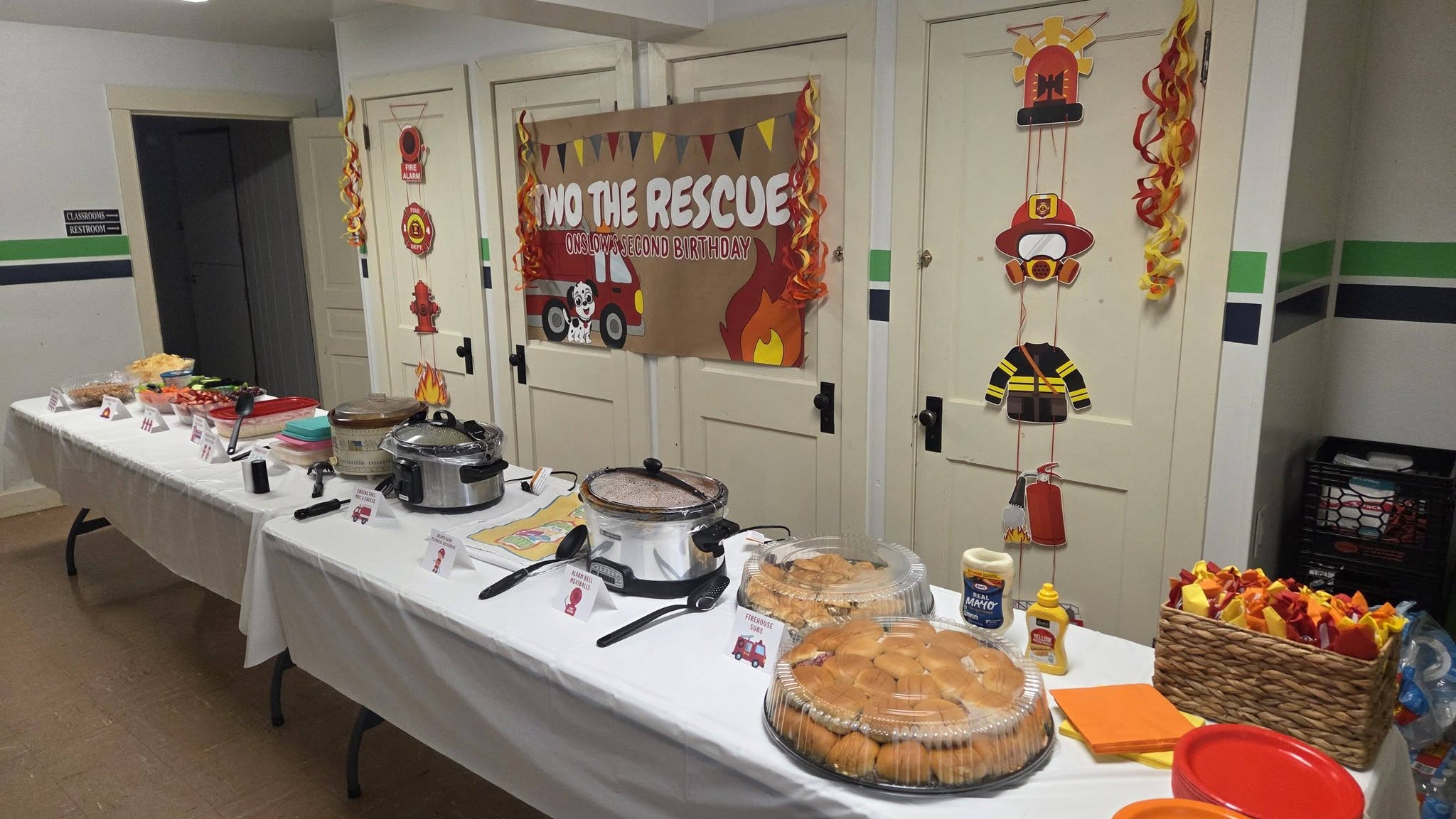 Two the Rescue themed birthday buffet table with crockpots, slider platters, and fire station decorations.