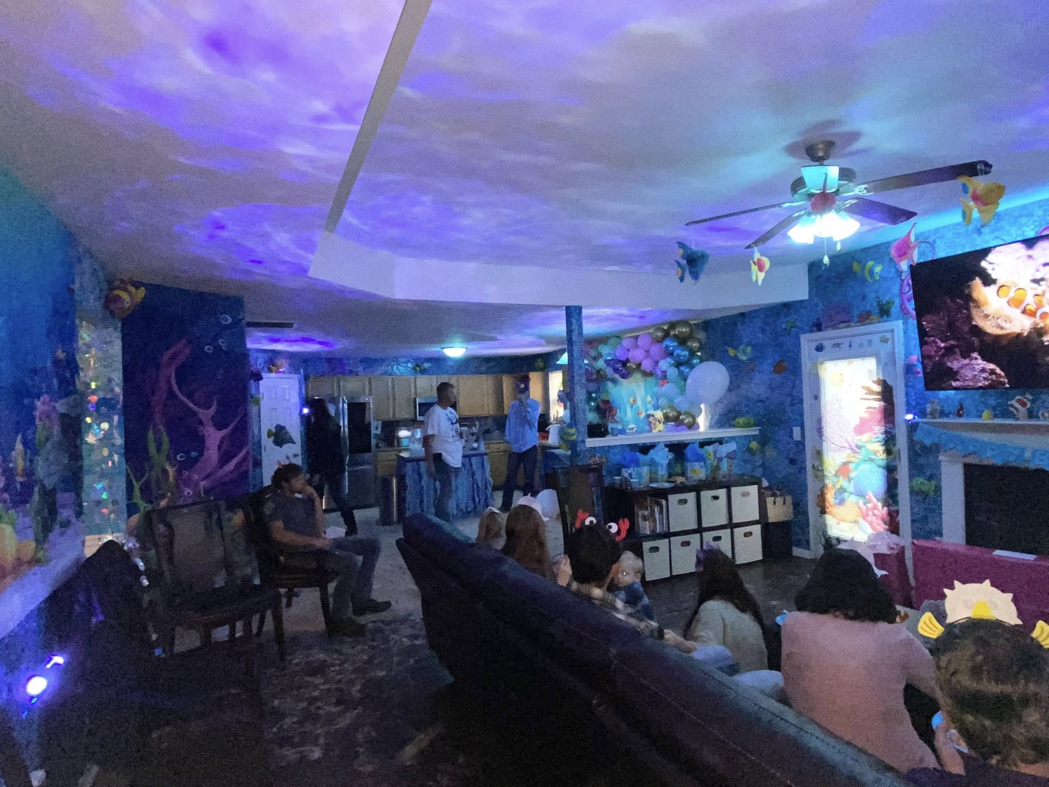 Living room decorated with ocean theme and blue light projector effects for a party