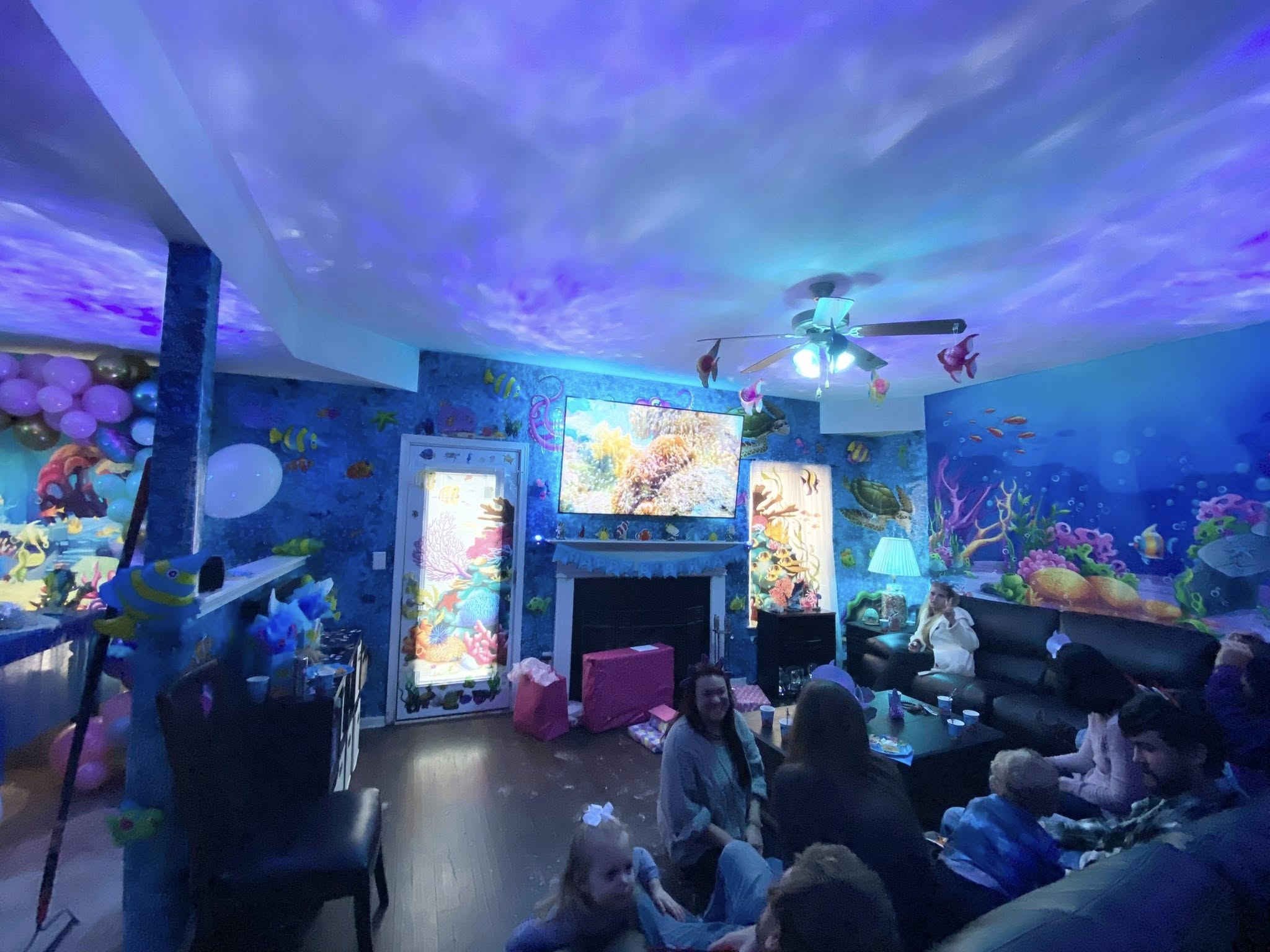 Living room decorated with an underwater ocean theme for a birthday party featuring blue wave lighting effects.
