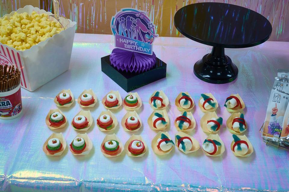 Table decorated for a theme party with popcorn, a Happy Birthday sign, and individual marshmallow treats.