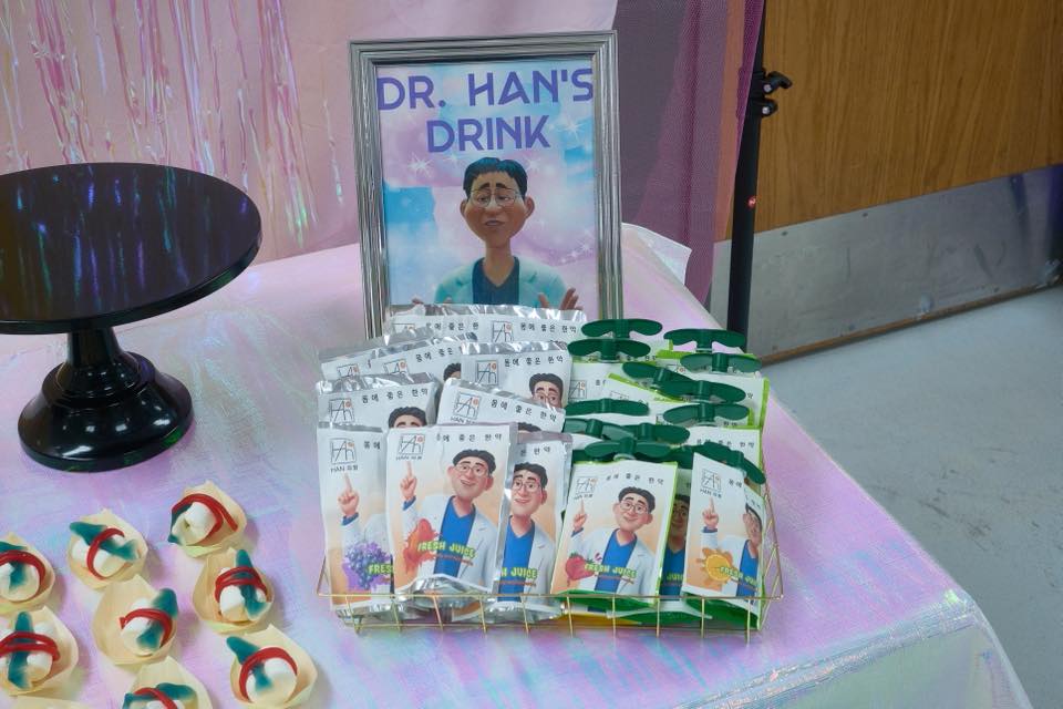 Display of Dr. Han's Drink fruit juice pouches with cartoon mascot in a gold wire basket.