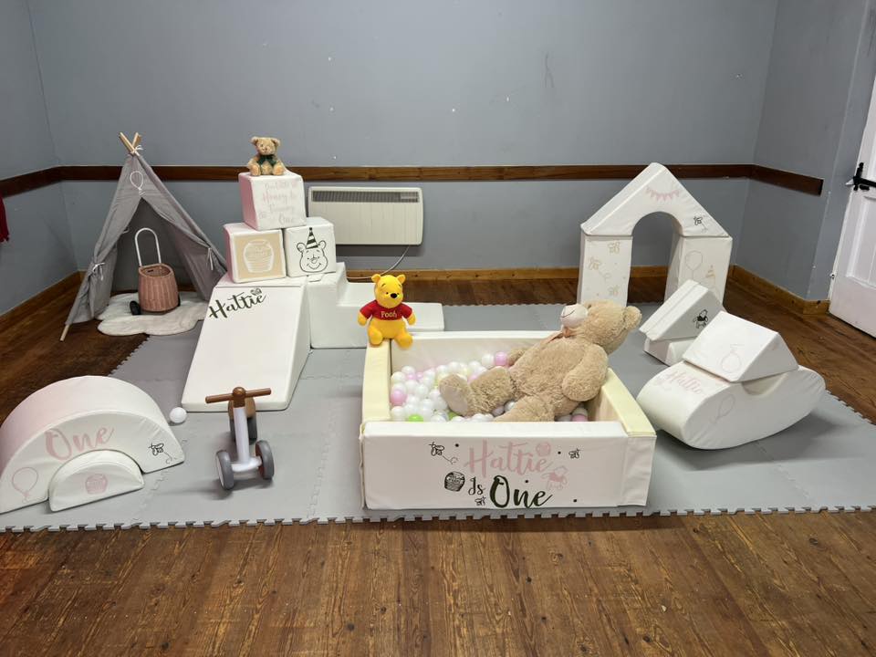 Soft play foam set decorated with Winnie the Pooh theme and Hattie is One text for a first birthday party