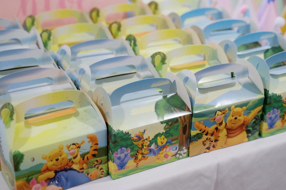 Winnie the Pooh themed favor boxes lined up on a white table.