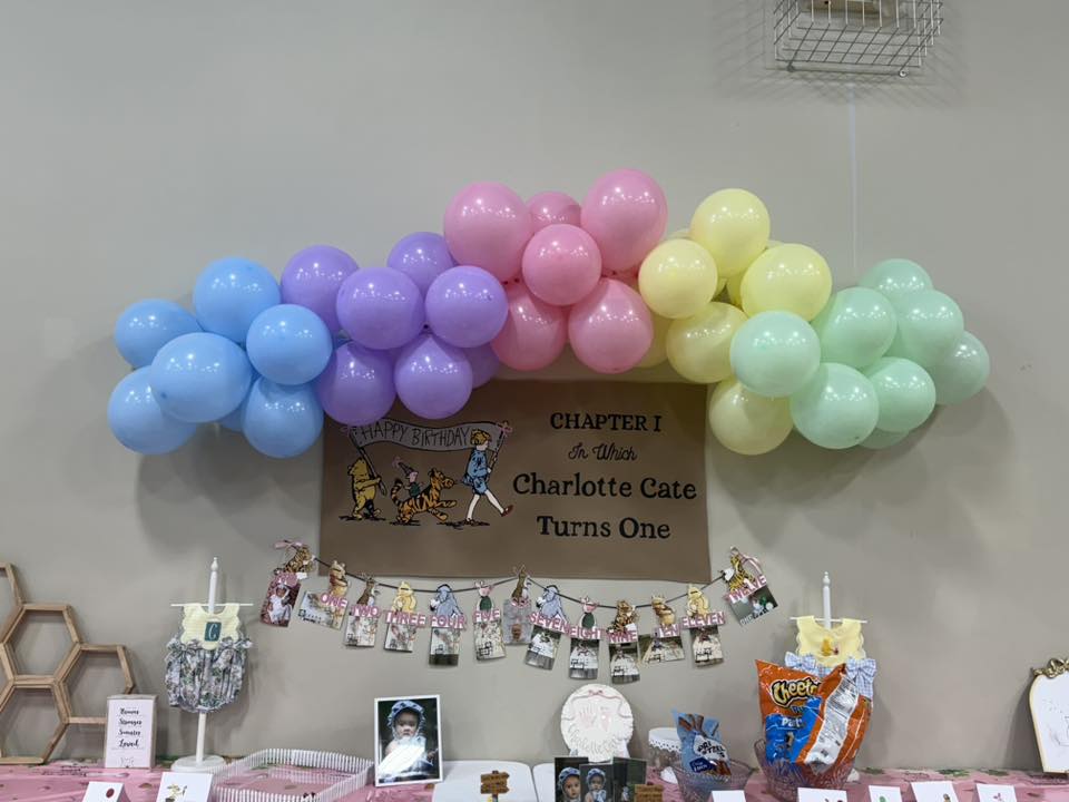 Pastel balloon arch and Winnie the Pooh themed first birthday party decor for Charlotte Cate