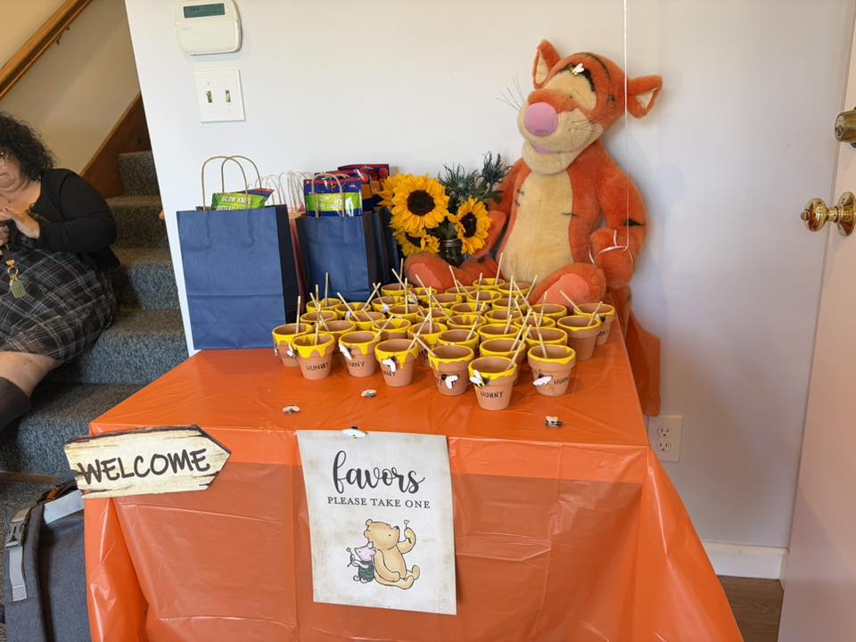 Winnie the Pooh themed party table with Tigger plush, sunflowers, and small Hunny pot party favors.