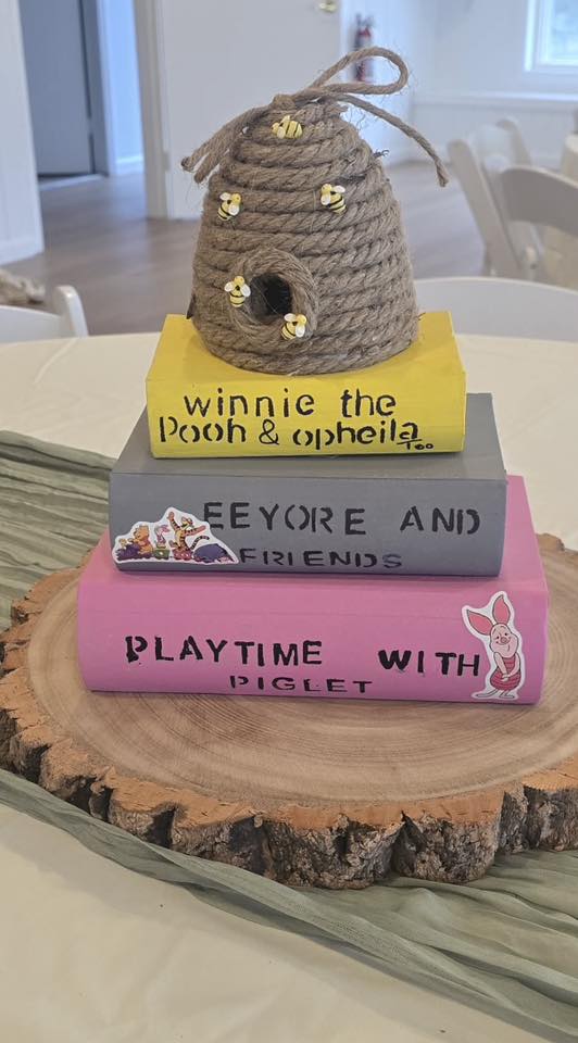 Tabletop decor set featuring a stacked book tower titled Winnie the Pooh and Piglet topped with a small rope beehive.