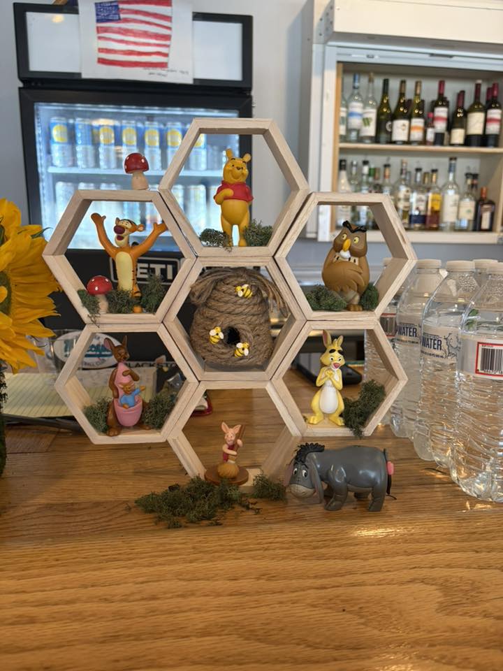 Honeycomb shelf display featuring Winnie the Pooh character figures and a miniature beehive.