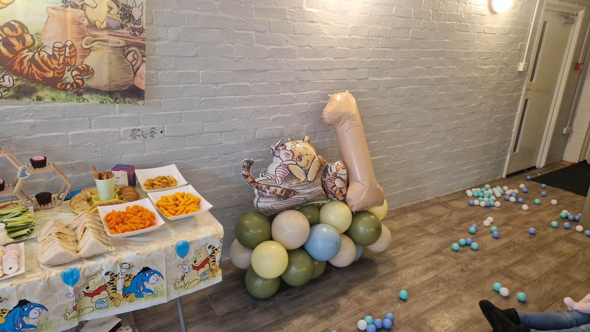 Winnie the Pooh themed party decorations with a number one balloon and colorful serving platters
