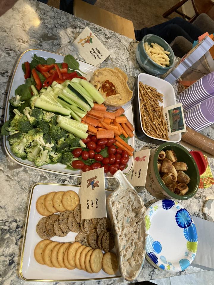 Table spread featuring Winnie the Pooh-themed snacks, including a vegetable tray, hummus, pretzels, and crackers.