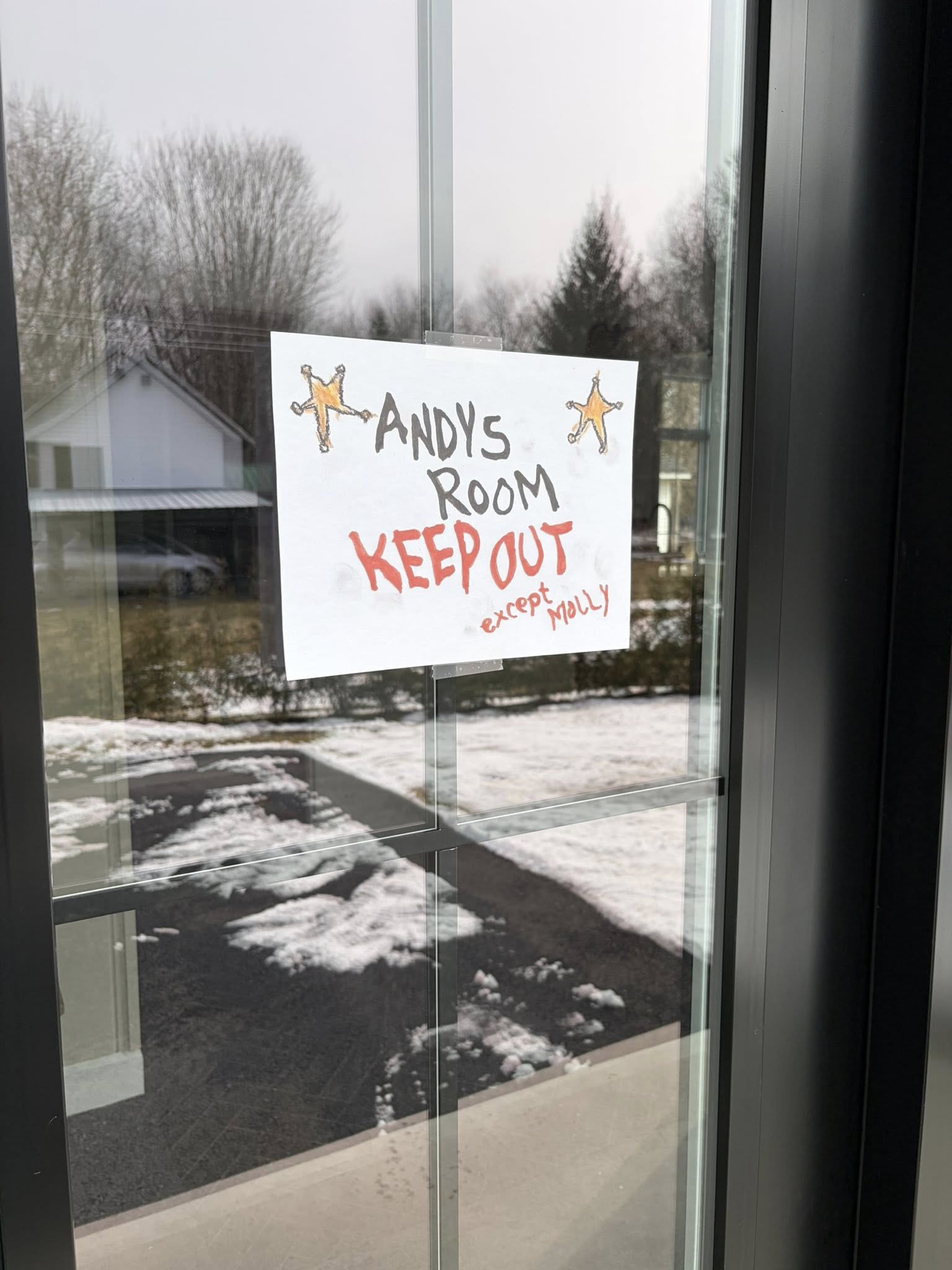 A handmade sign on a glass door that reads Andy's Room Keep Out except Molly with drawings of two sheriff badges.