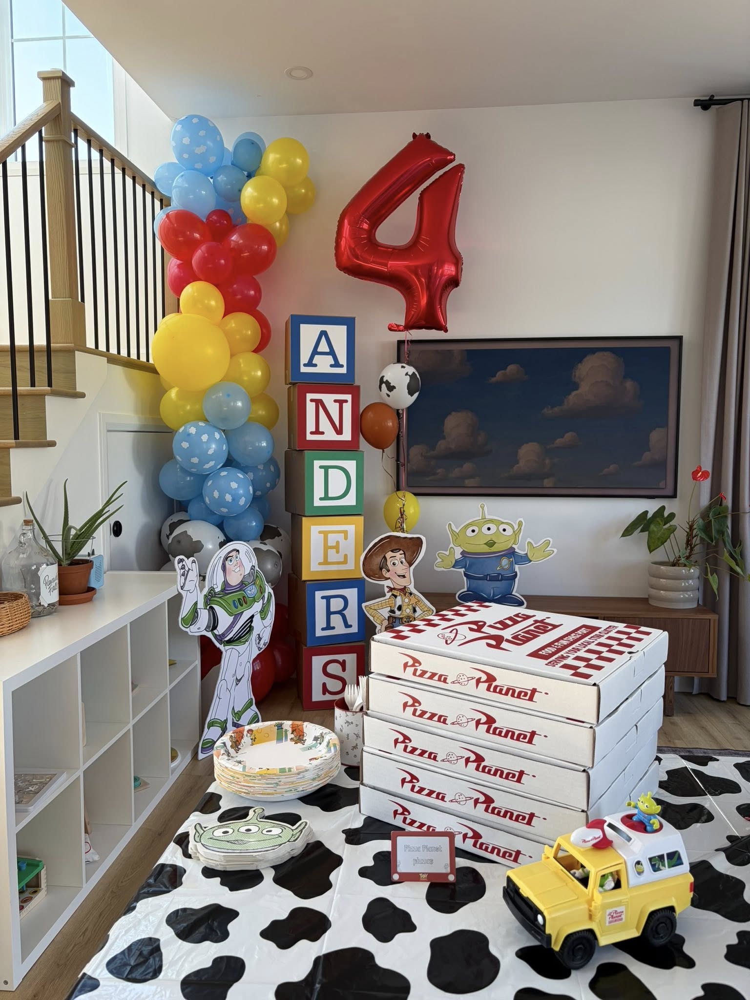 Toy Story themed birthday party setup with stacked Pizza Planet boxes and decorative character cutouts