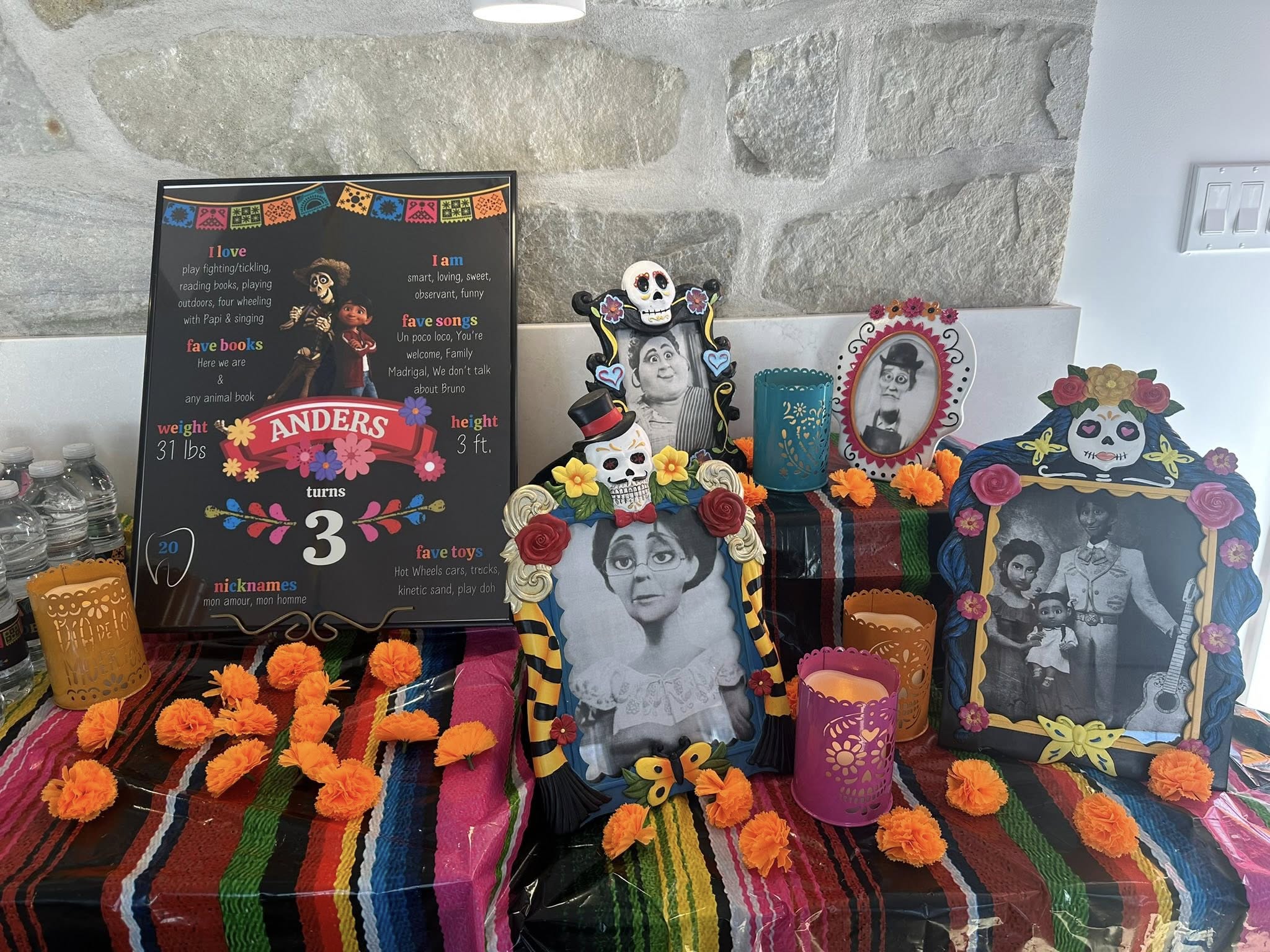 Dia de los Muertos themed third birthday party display with Coco-inspired decor, framed family photos, and marigolds