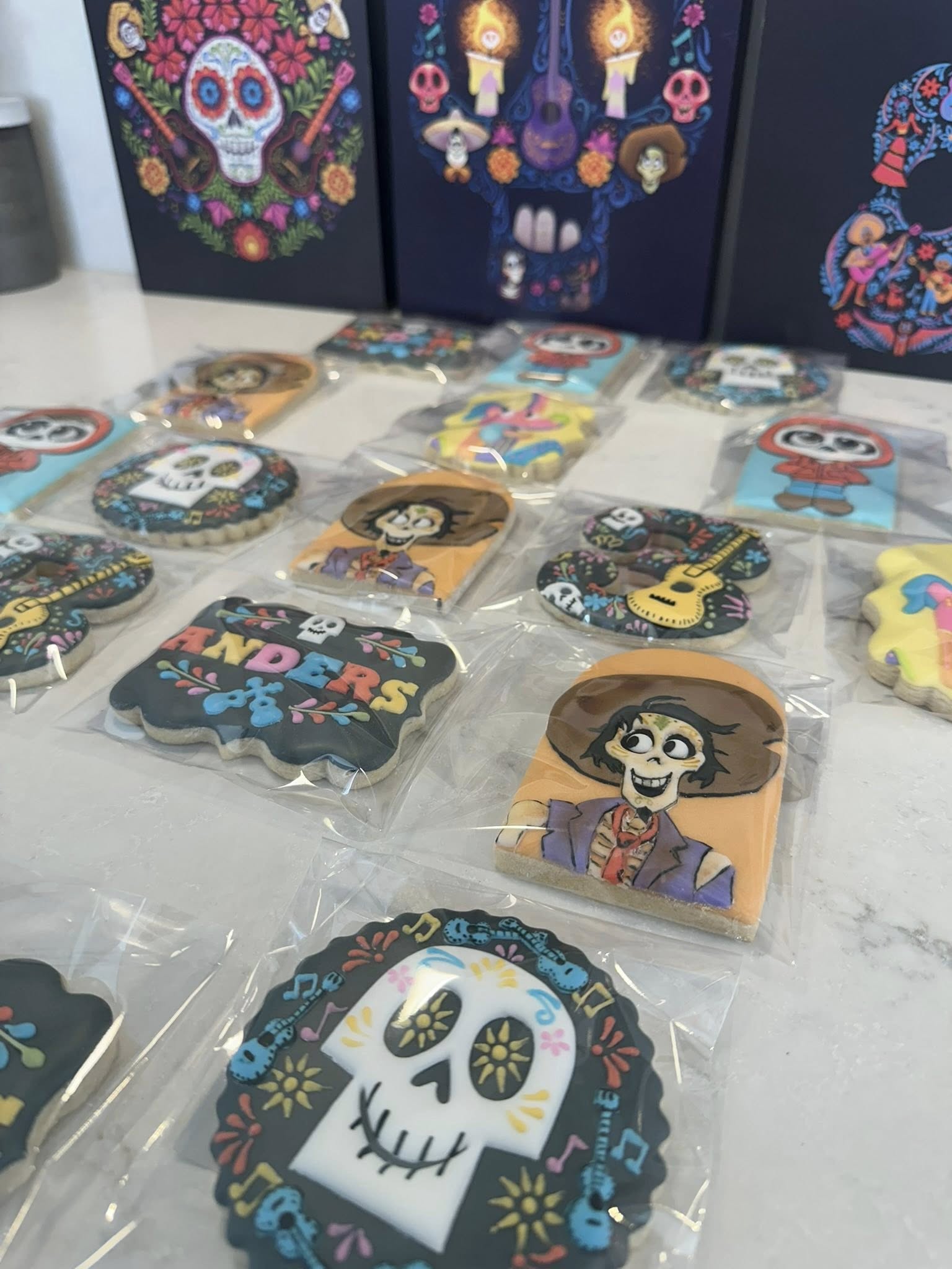 Set of Coco-themed sugar cookies decorated with characters, skulls, and musical designs in clear plastic packaging.
