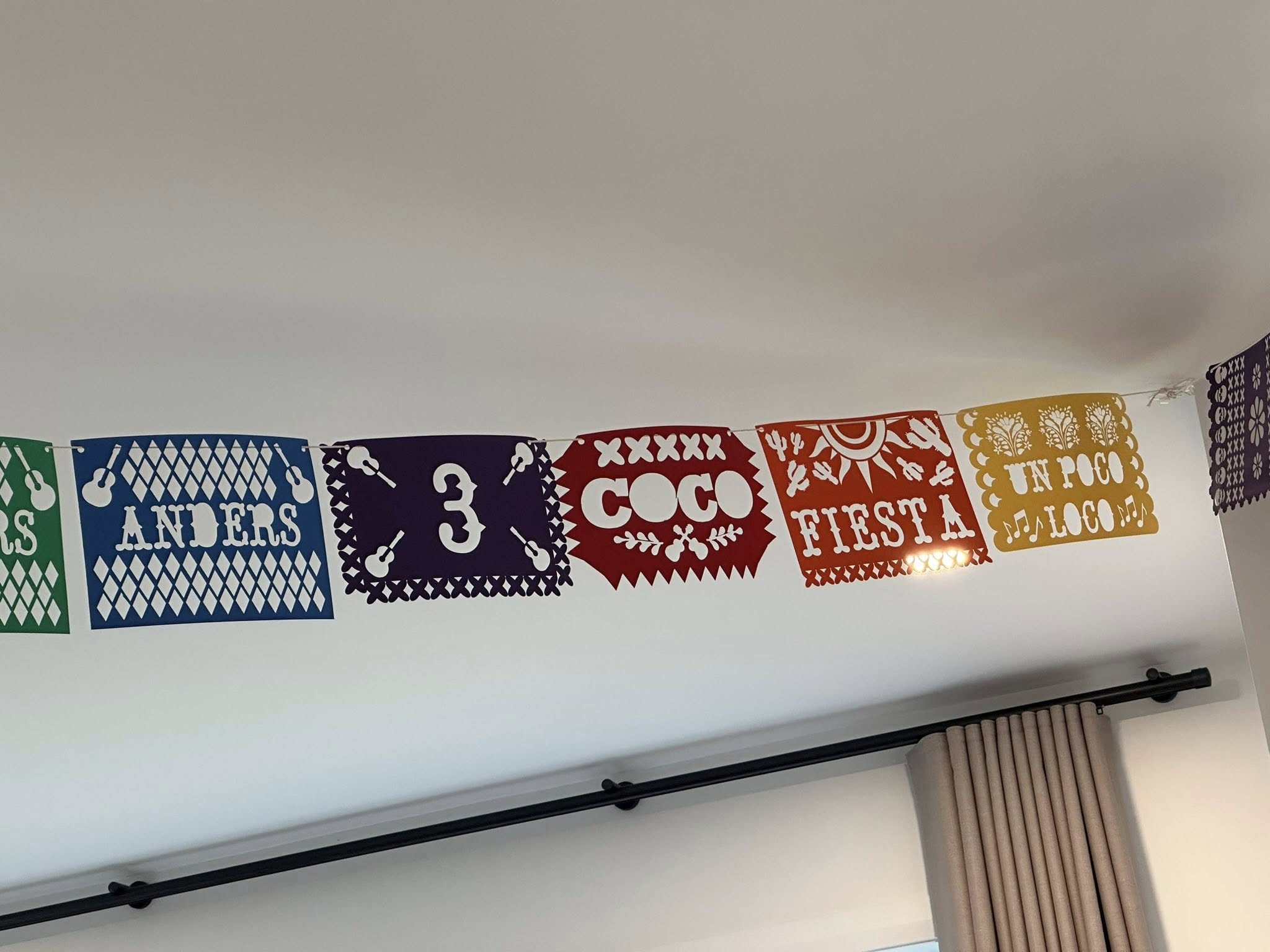 Custom Coco-themed birthday bunting with name Anders, the number 3, and fiesta phrases hanging on a wall