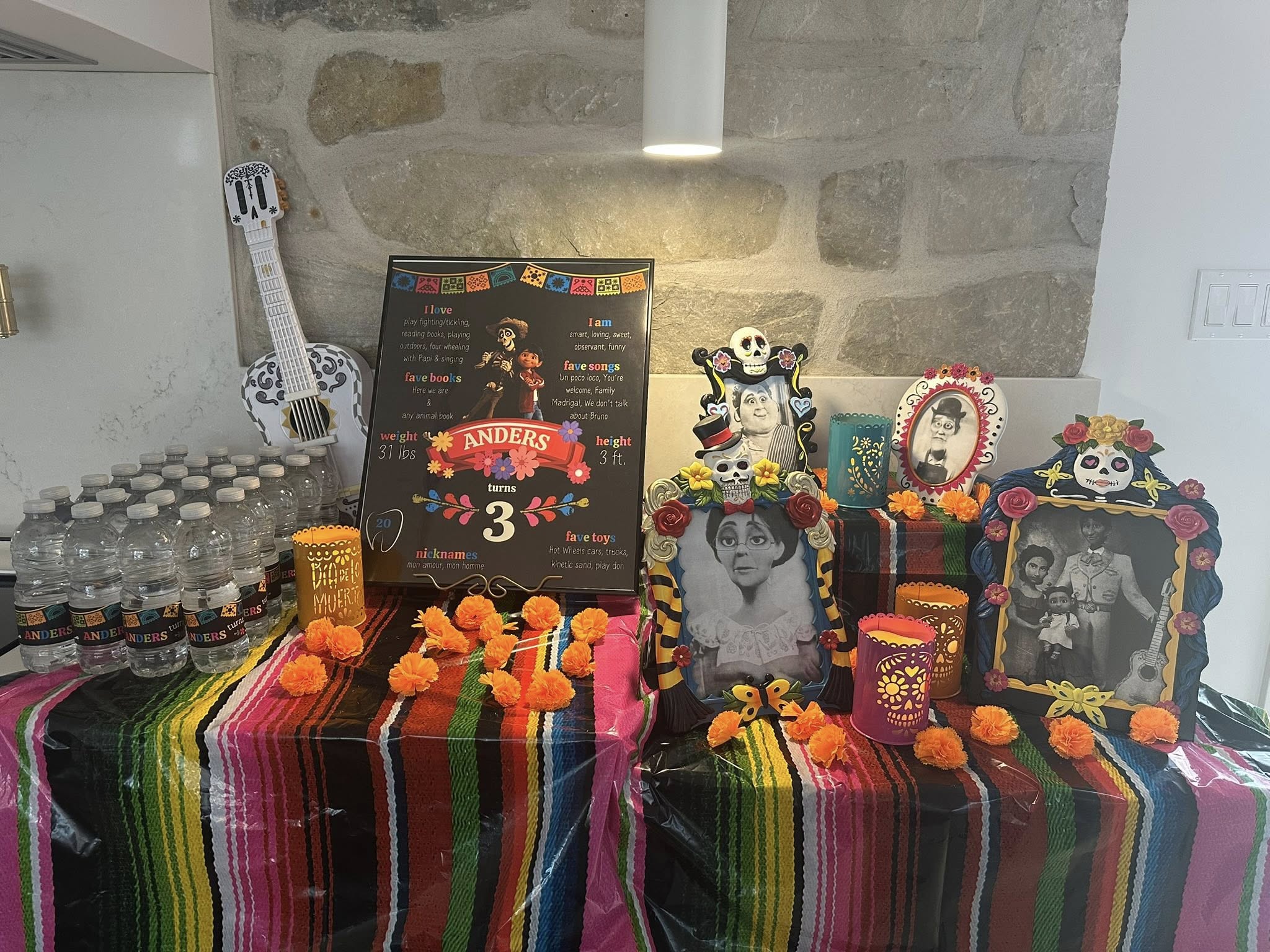 Coco-themed third birthday party display with personal milestone board, family photos in sugar skull frames, and marigolds