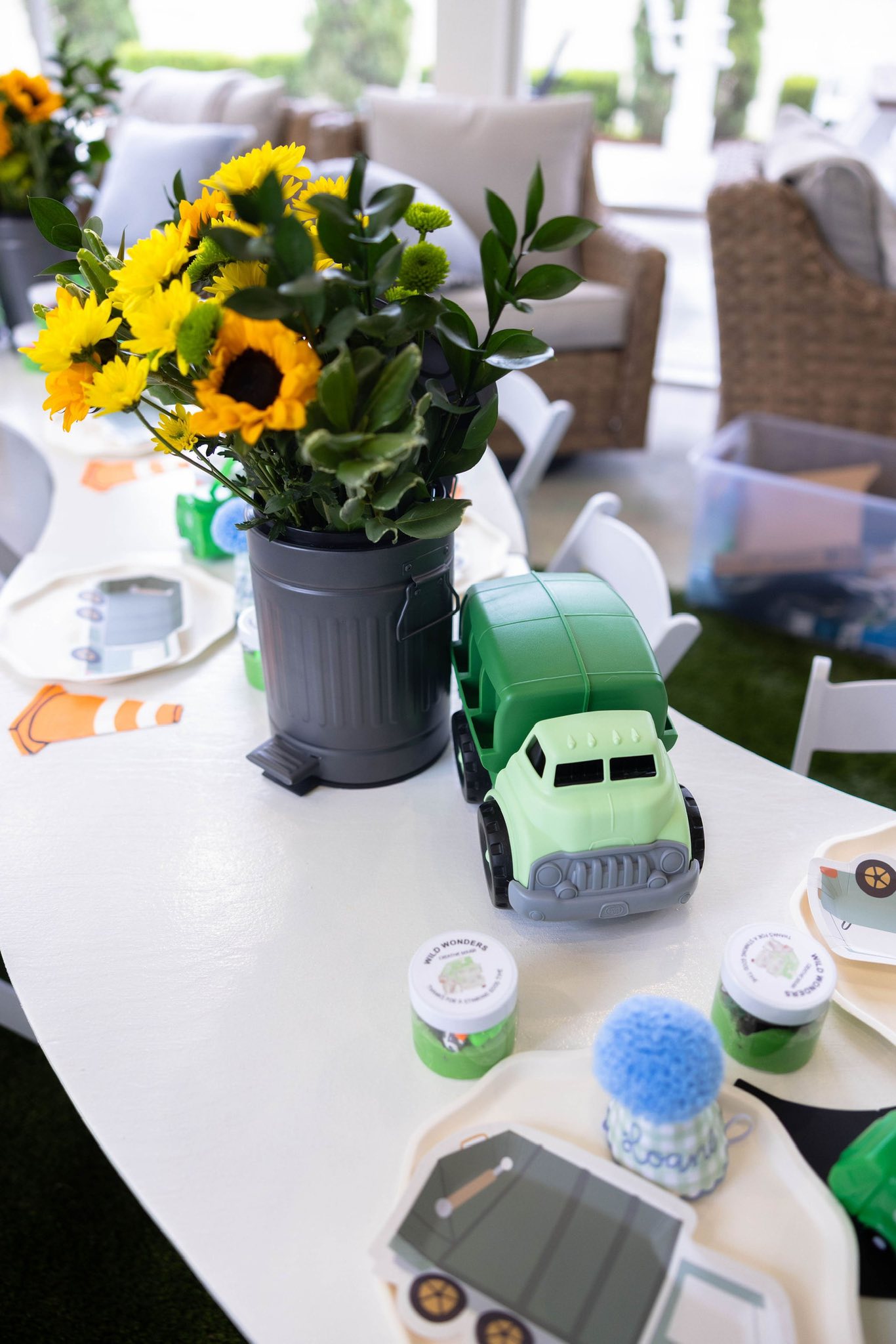 Table setting themed with a toy garbage truck, sunflower centerpiece, and construction-themed party plates.
