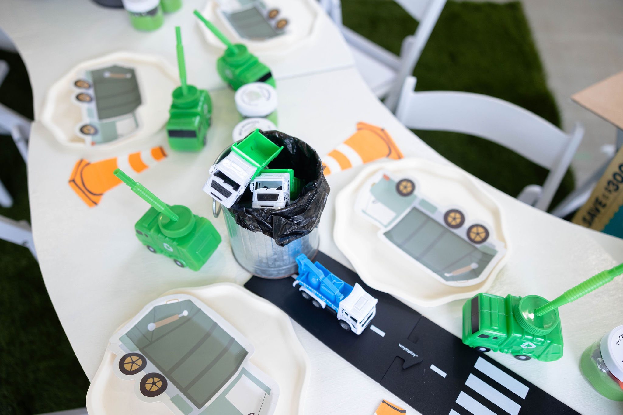 Table setting themed for a trash truck birthday party with truck-shaped plates and garbage truck drink cups