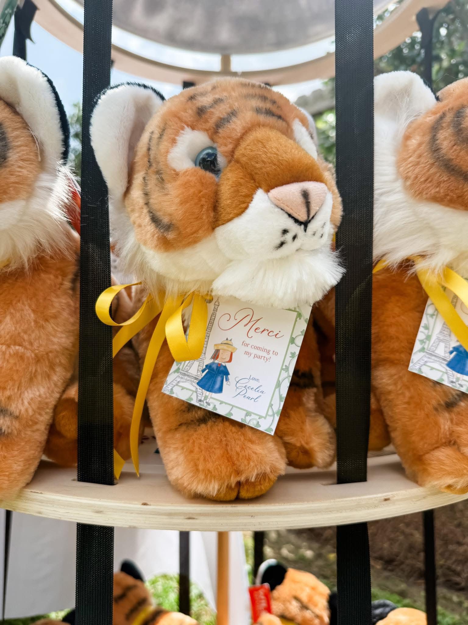 Plush tiger party favor with a Merci thank you tag tied with a yellow ribbon