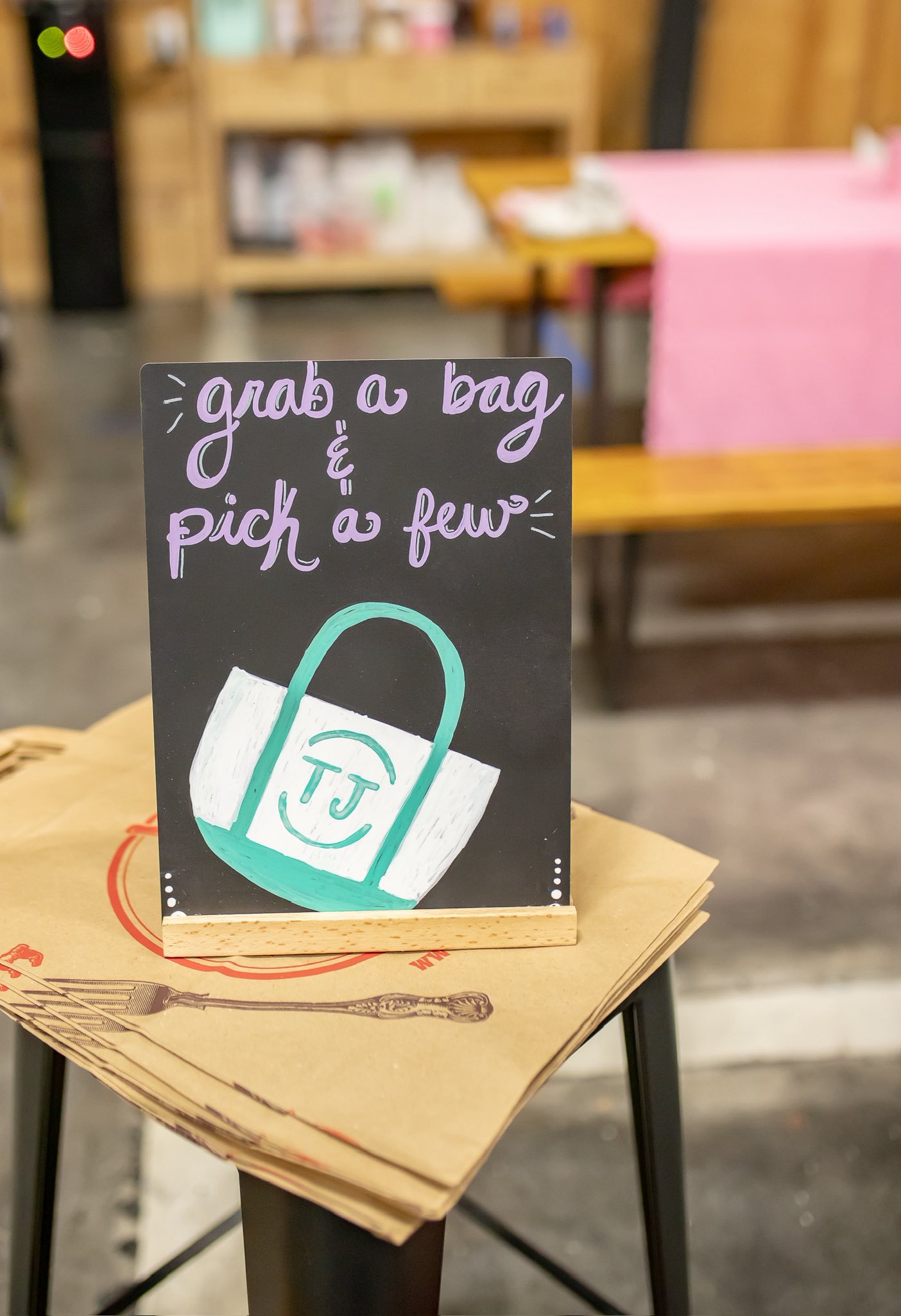 Chalkboard sign reading grab a bag and pick a few resting on a stack of paper bags.