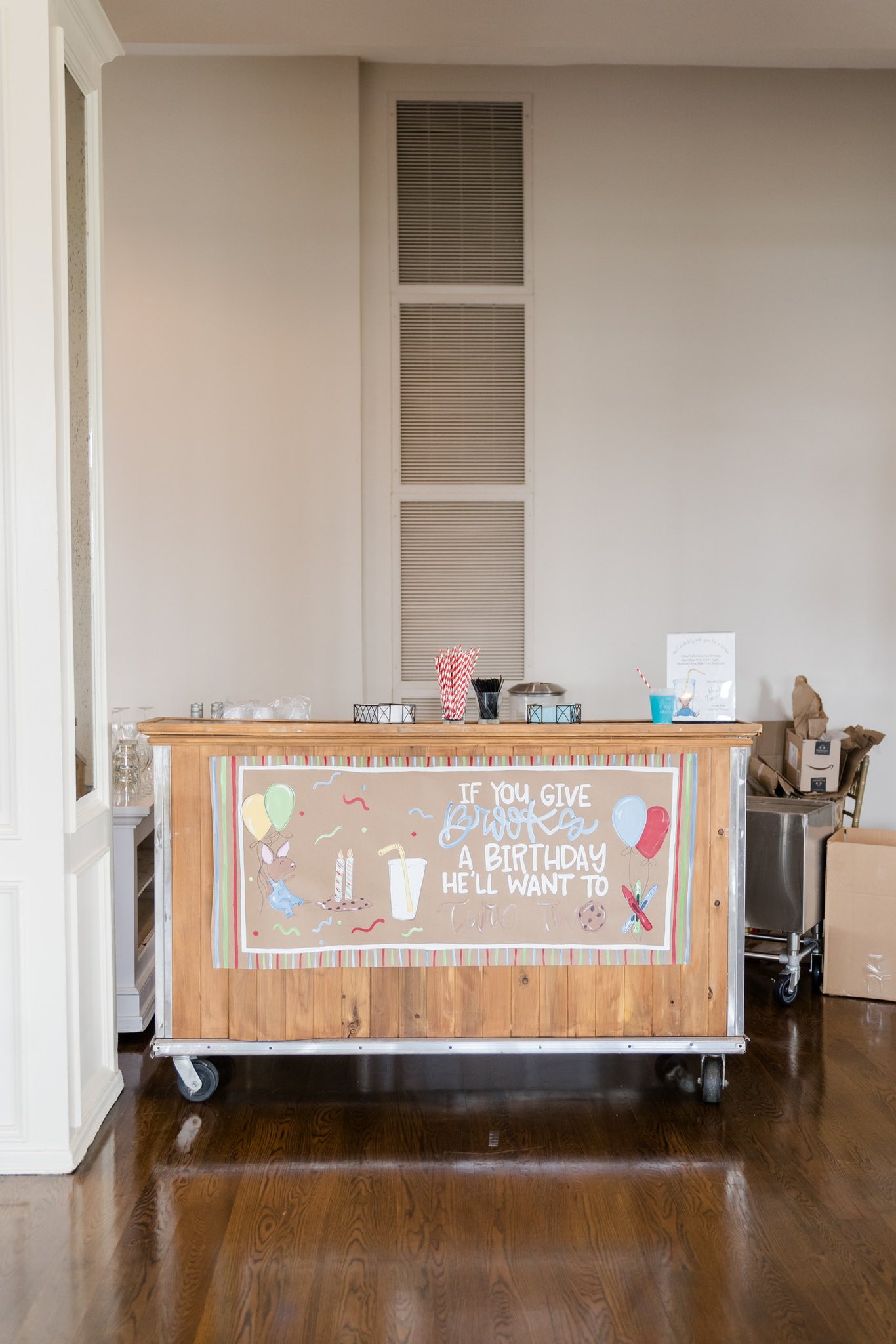 Mobile wooden bar cart decorated with a personalized sign for a child's second birthday party.