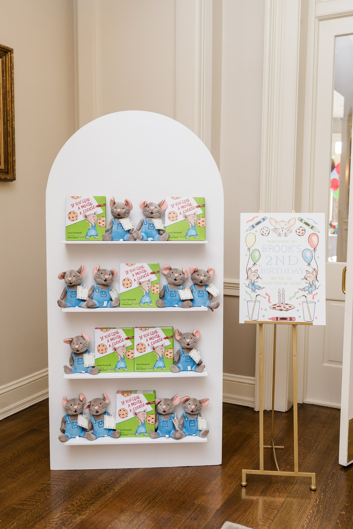 Display of If You Give a Mouse a Cookie books and plush toys at a toddler birthday party.