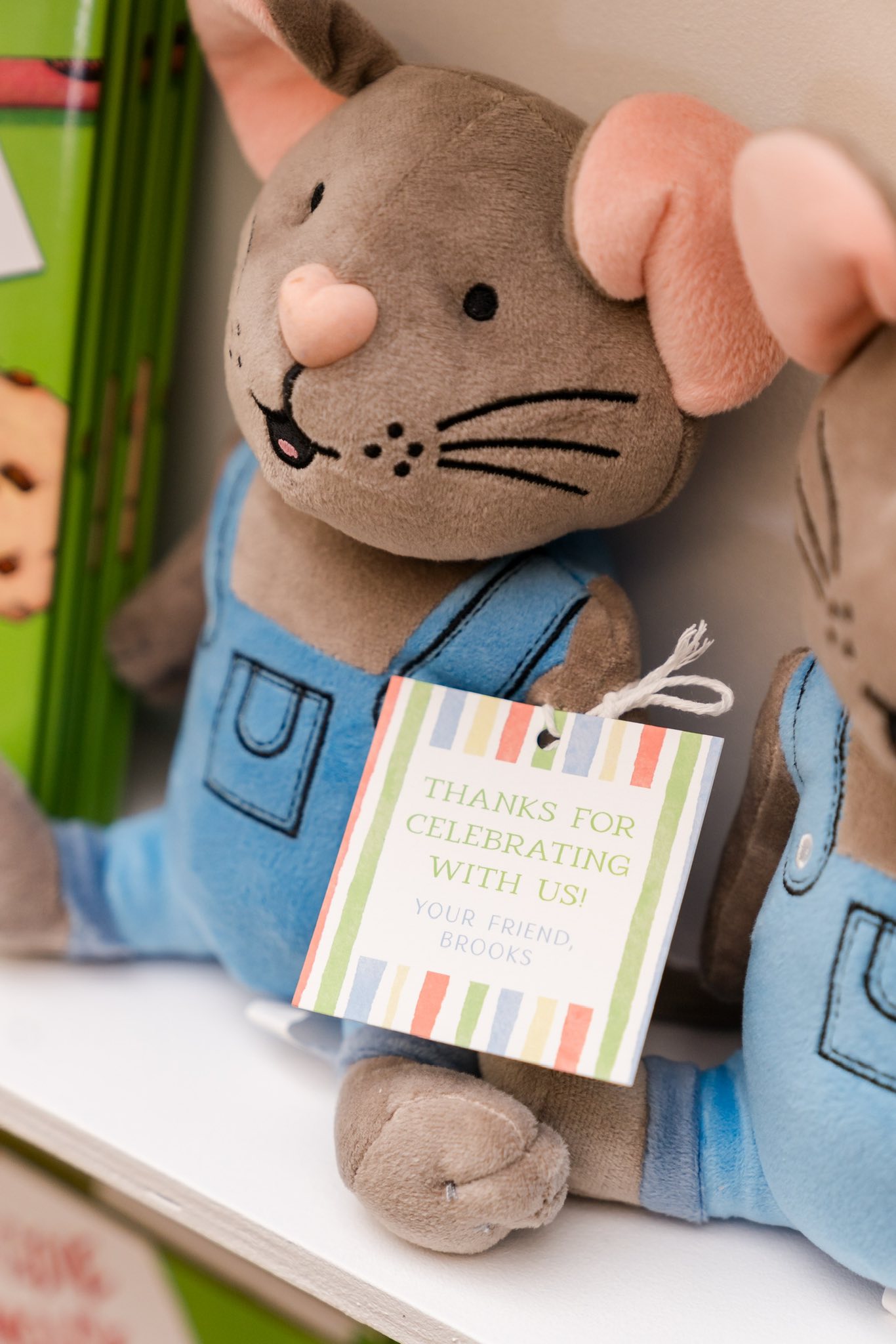 Plush brown mouse wearing blue overalls with a striped thank you tag.