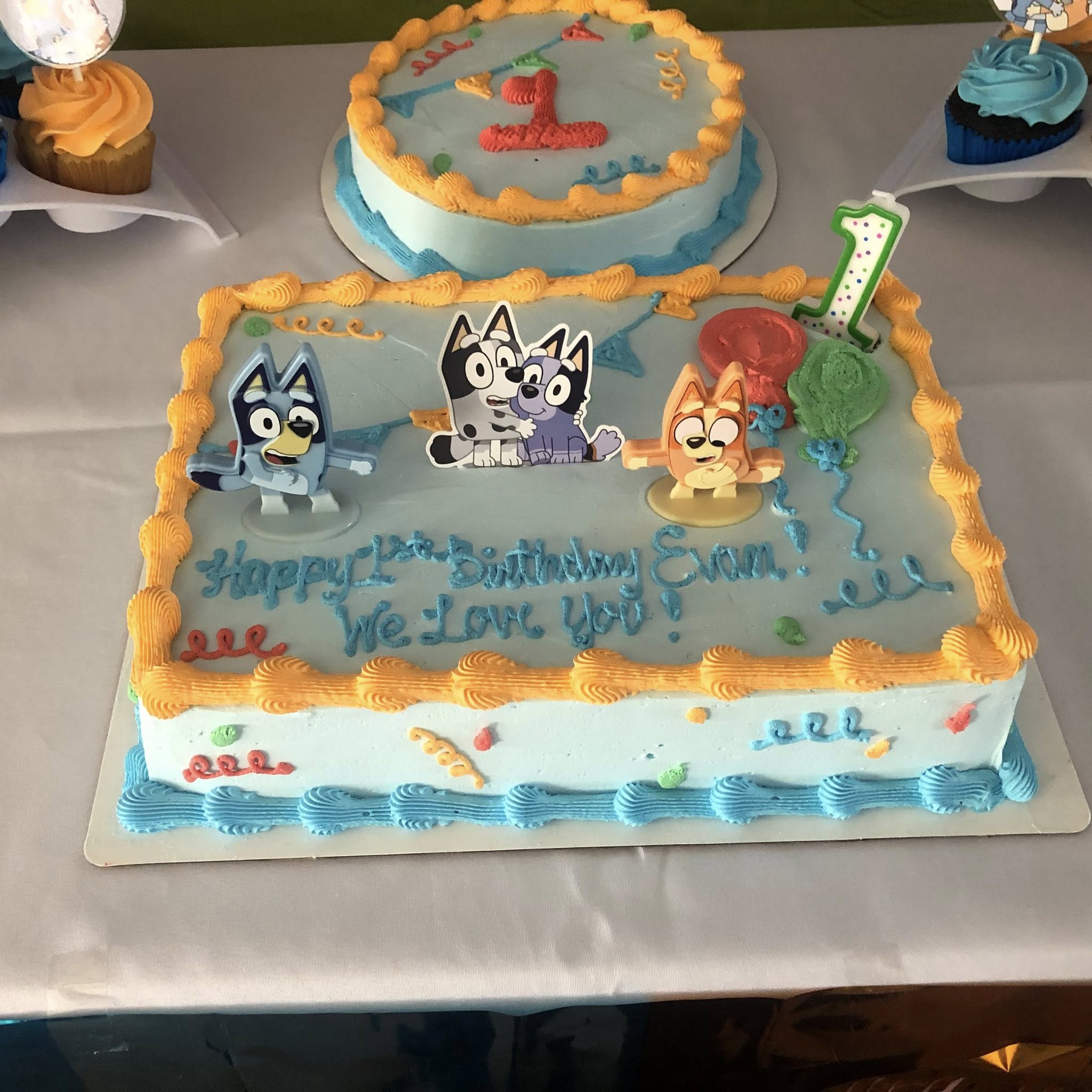 Bluey themed rectangular sheet cake for first birthday with Bluey, Bingo, and Bandit character toppers