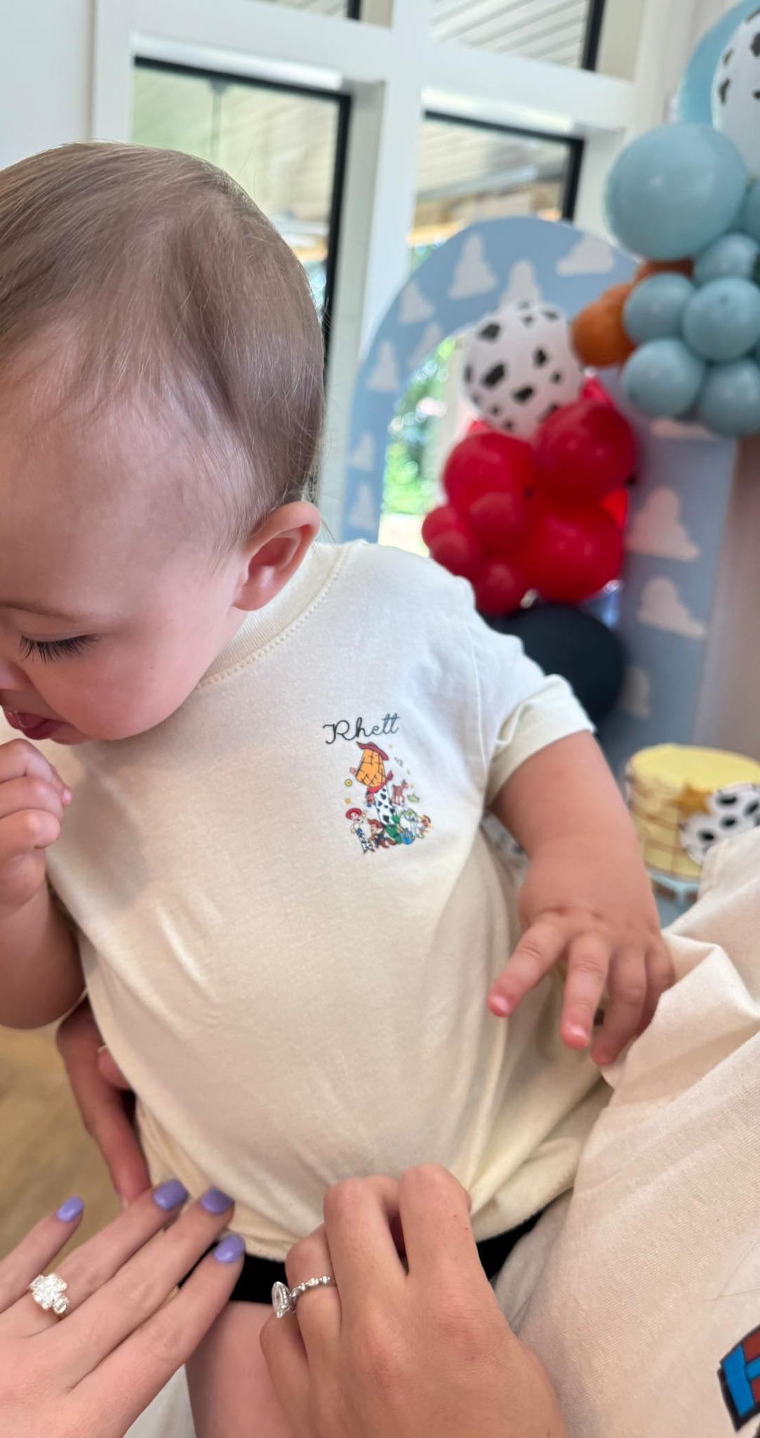Baby wearing a beige personalized t-shirt with a vintage Toy Story character print and the name Rhett.