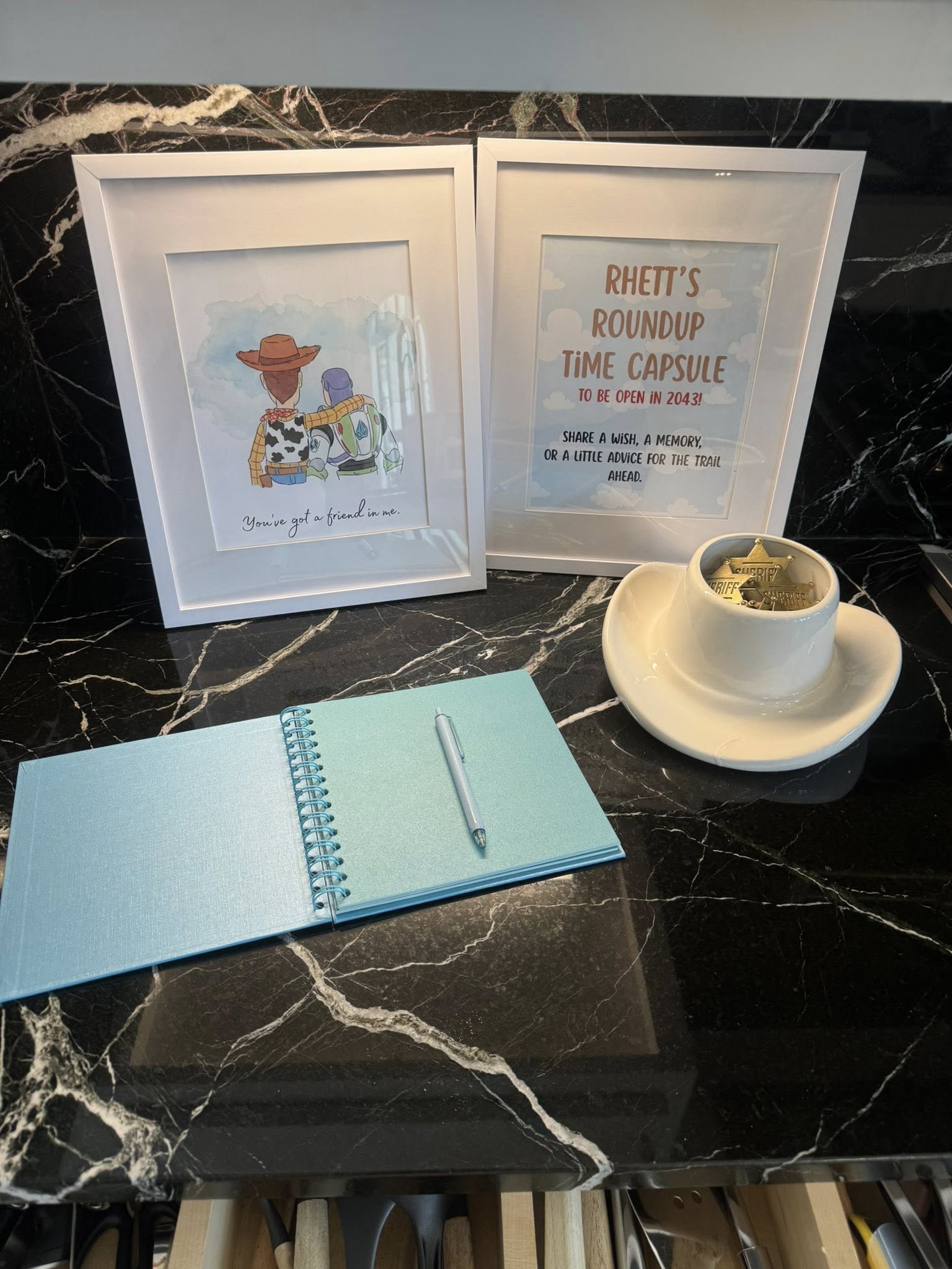 Toy Story inspired time capsule display with framed signs, a guest book, and a miniature sheriff hat with badges.