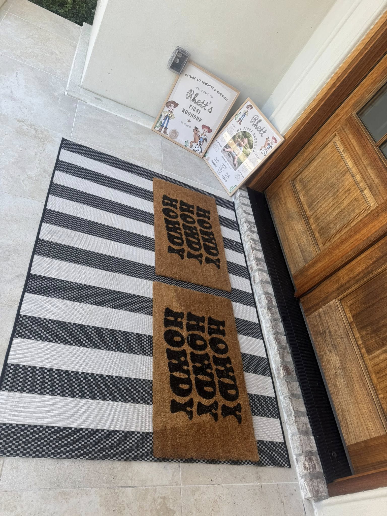Two layered porch rugs featuring black and white striped base rug and Howdy coir doormats with party signs.
