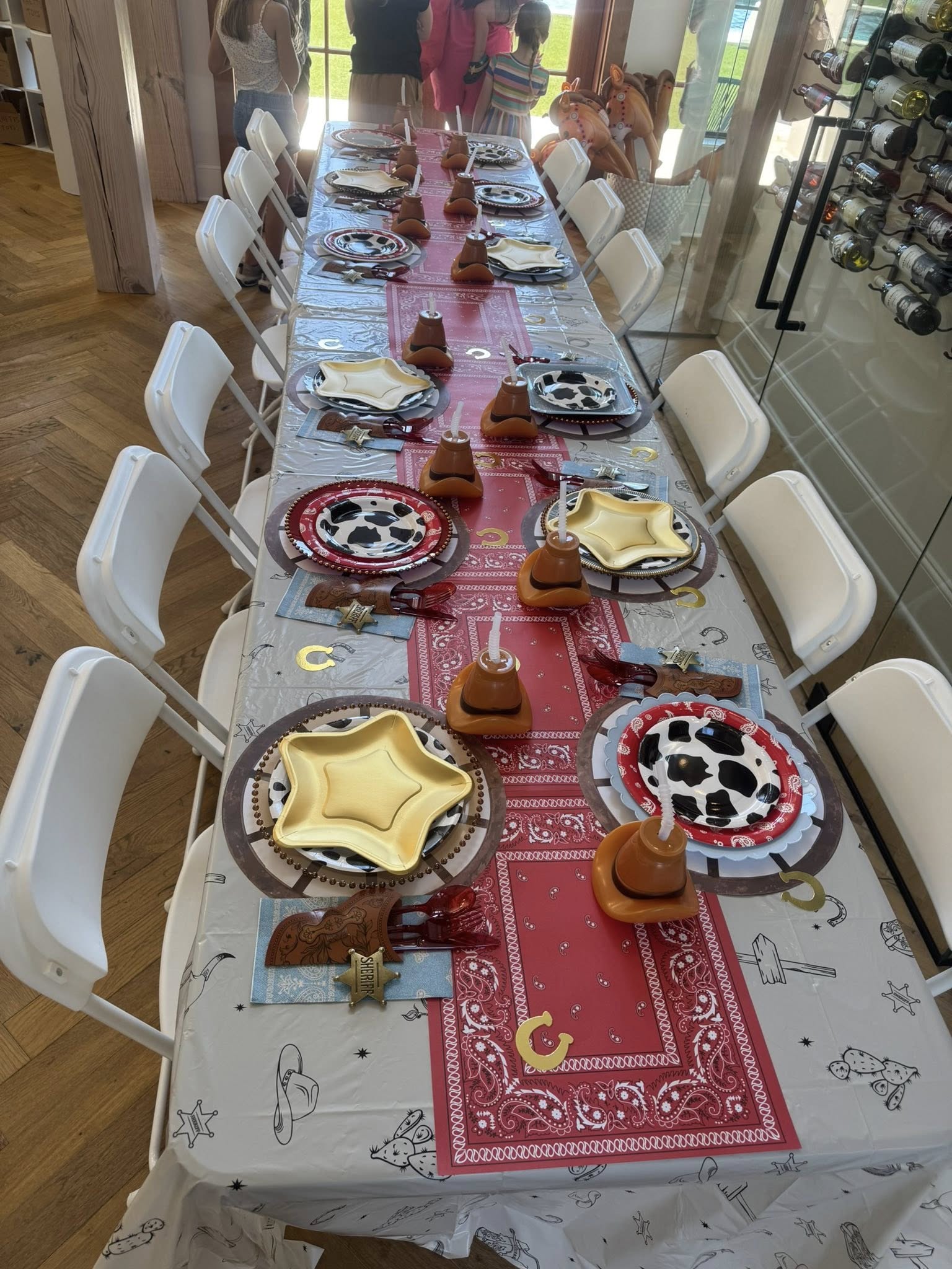 Dining table set for a western-themed party with cow print plates, gold star plates, and cowboy hat centerpieces.